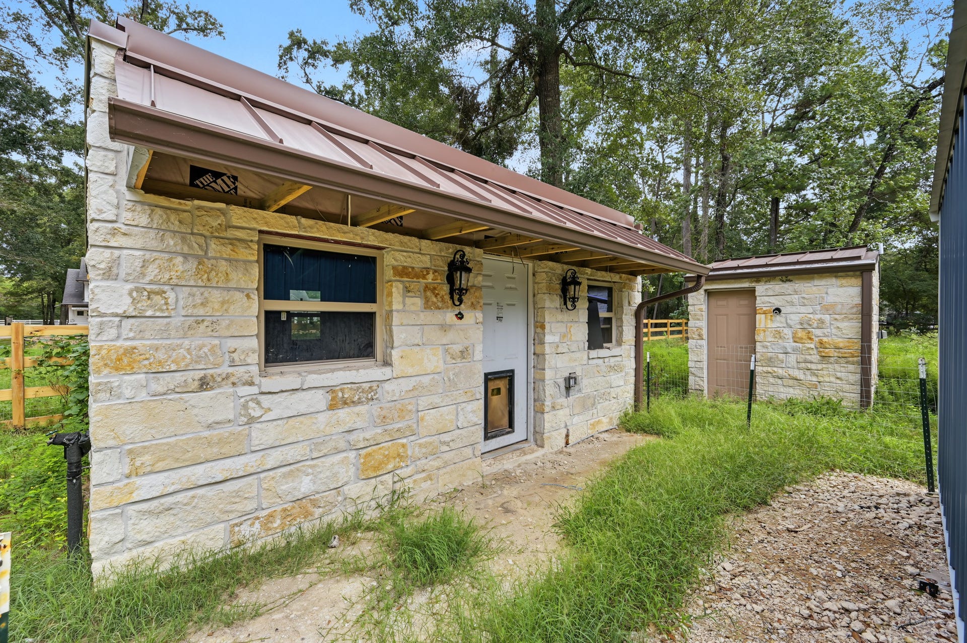 Charming stone dog house with A/C and electricity with unfinished ceiling and a metal roof.