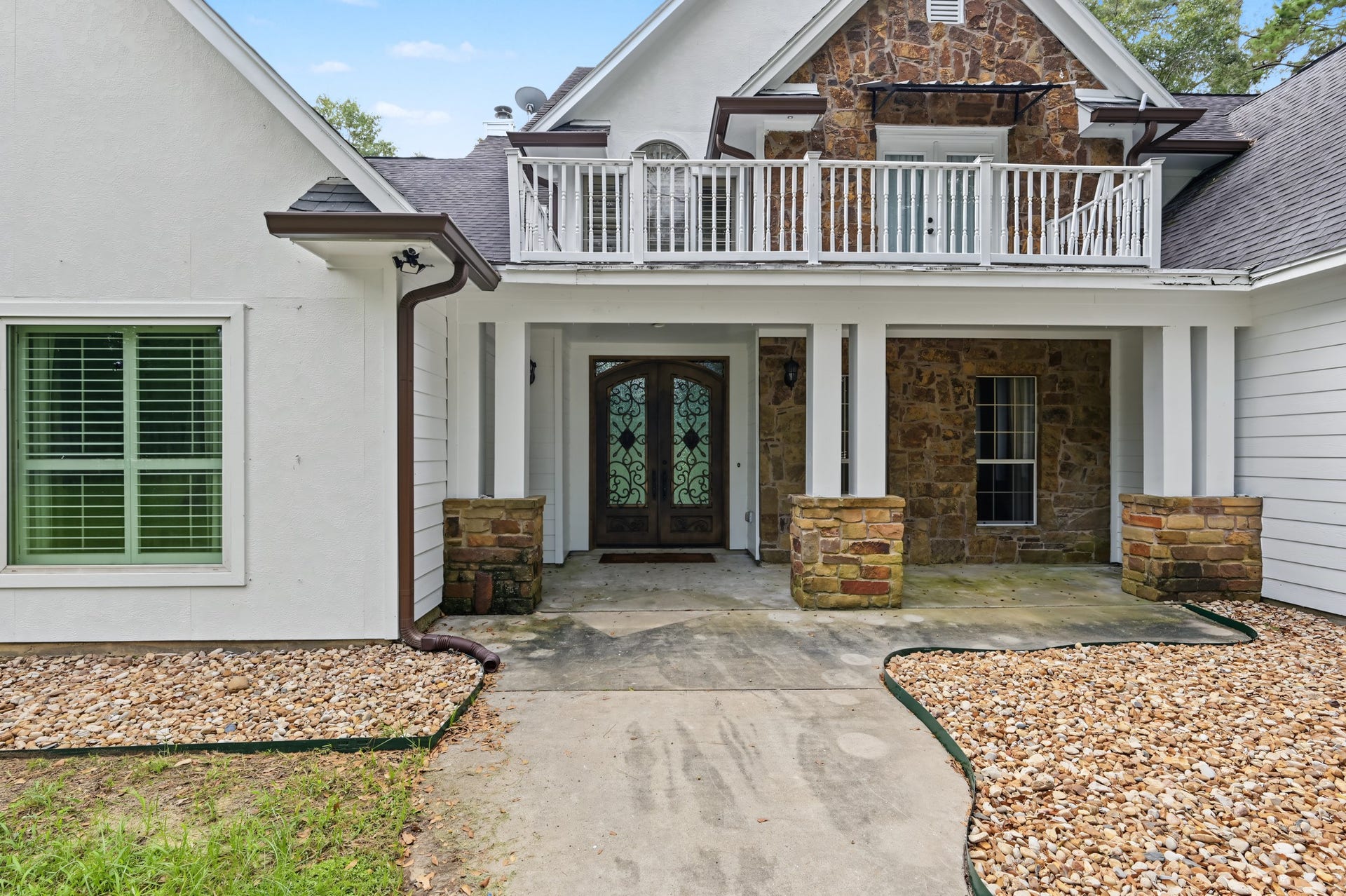 Welcoming stone-accented entrance, elegant double doors, and a spacious upper balcony.
