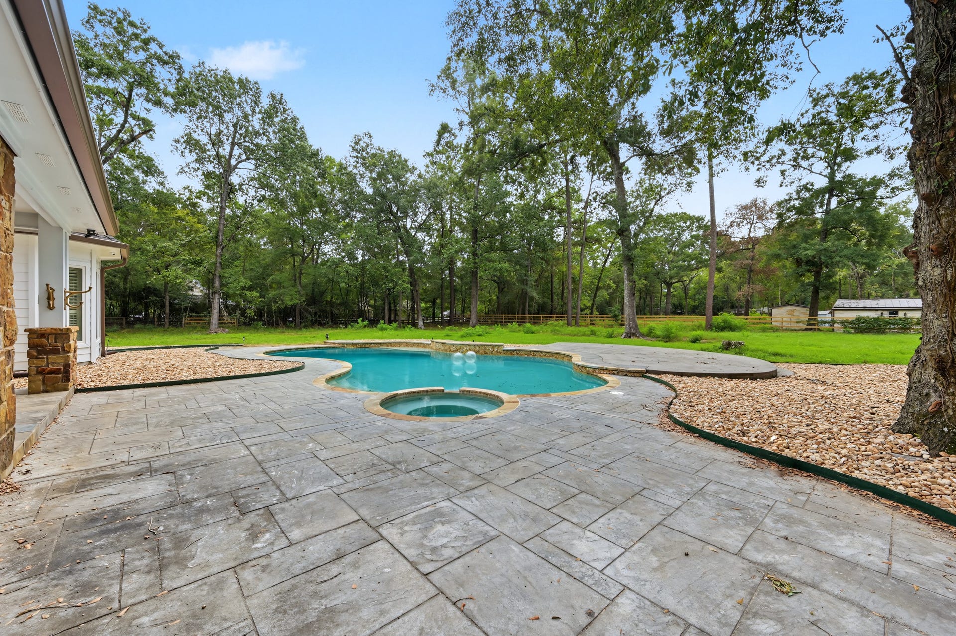 Experience luxury with this stunning backyard oasis featuring an inviting pool surrounded by lush greenery and elegant stonework, perfect for relaxation and entertaining.