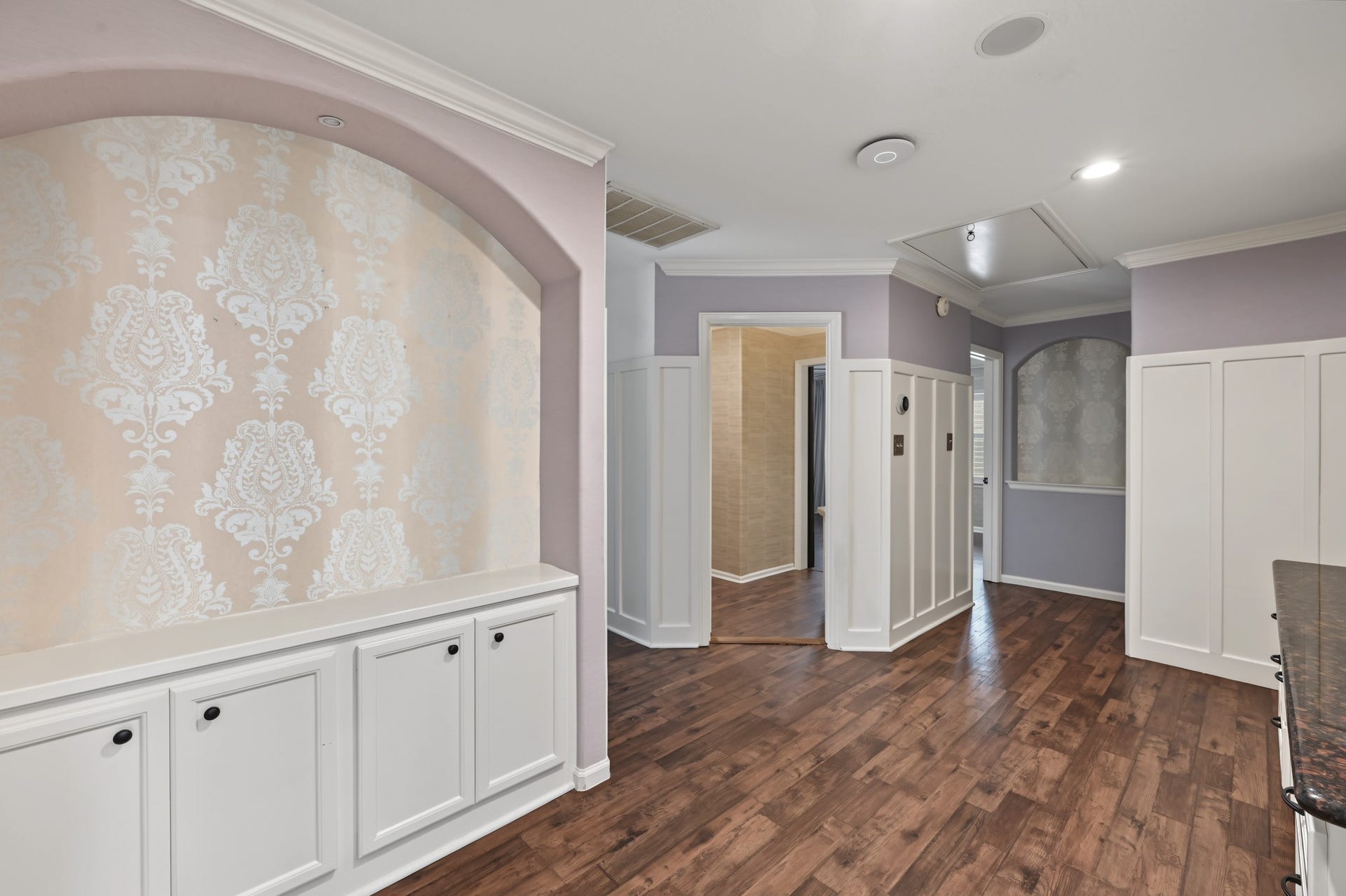 Charming hallway upstairs with elegant wainscoting, warm hardwood floors, and a decorative alcove, perfect for showcasing art or collectibles.