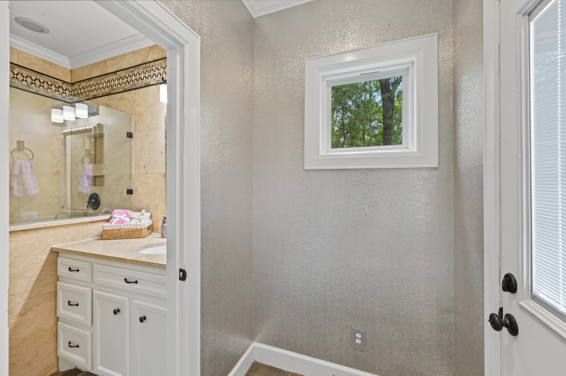 Elegant bathroom featuring a chic vanity with ample storage, accented by sleek marble countertops and a stylishly tiled shower.