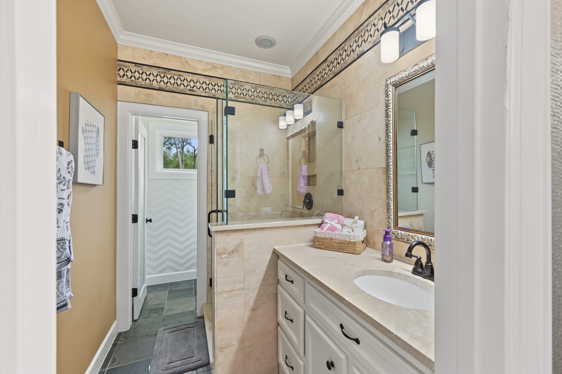 Elegant full bathroom just off the backyard/pool area, featuring a luxurious glass-enclosed shower, stylish tilework, and a sleek vanity with ample storage.