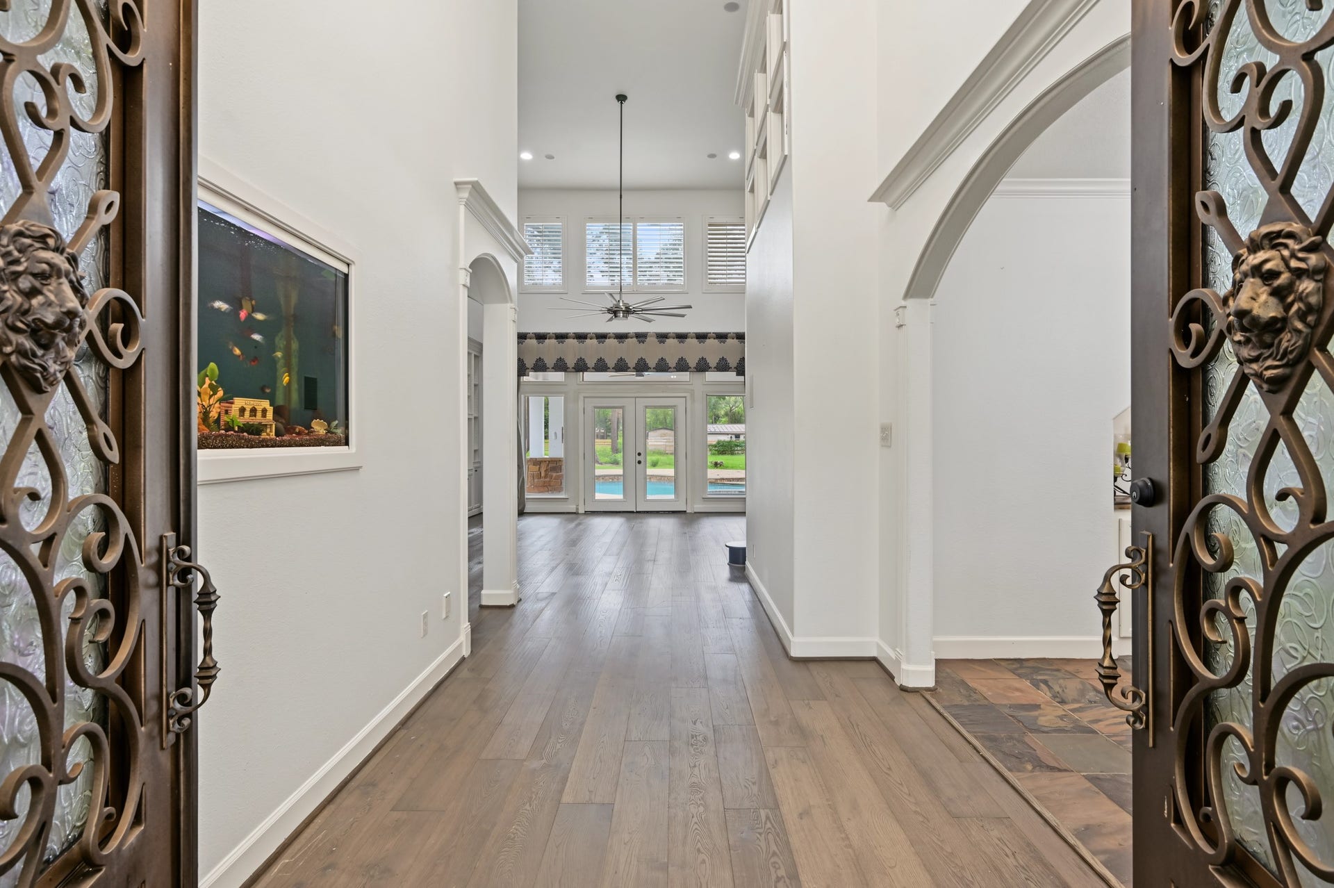 Stunning entryway with elegant wrought iron doors, high ceilings, and hardwood floors leading to a bright living area with pool views. Also a inwall aquarium with it's own self feeding and cleaning system.