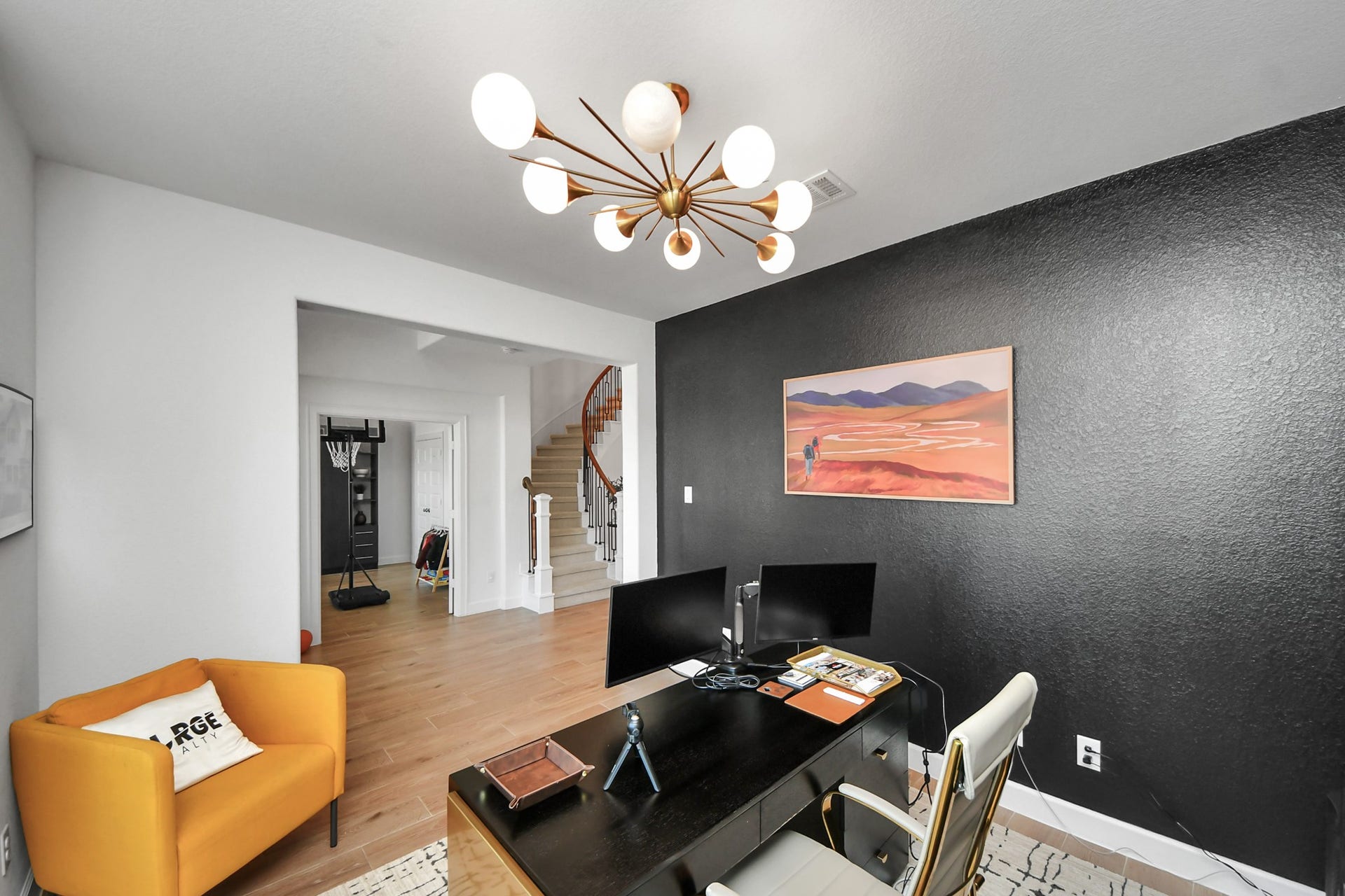 5542 Fairfield Lane, Pasadena, TX 77505 Stylish home office featuring a bold black accent wall, modern light fixture, and warm wood flooring, with an inviting open view to the staircase.