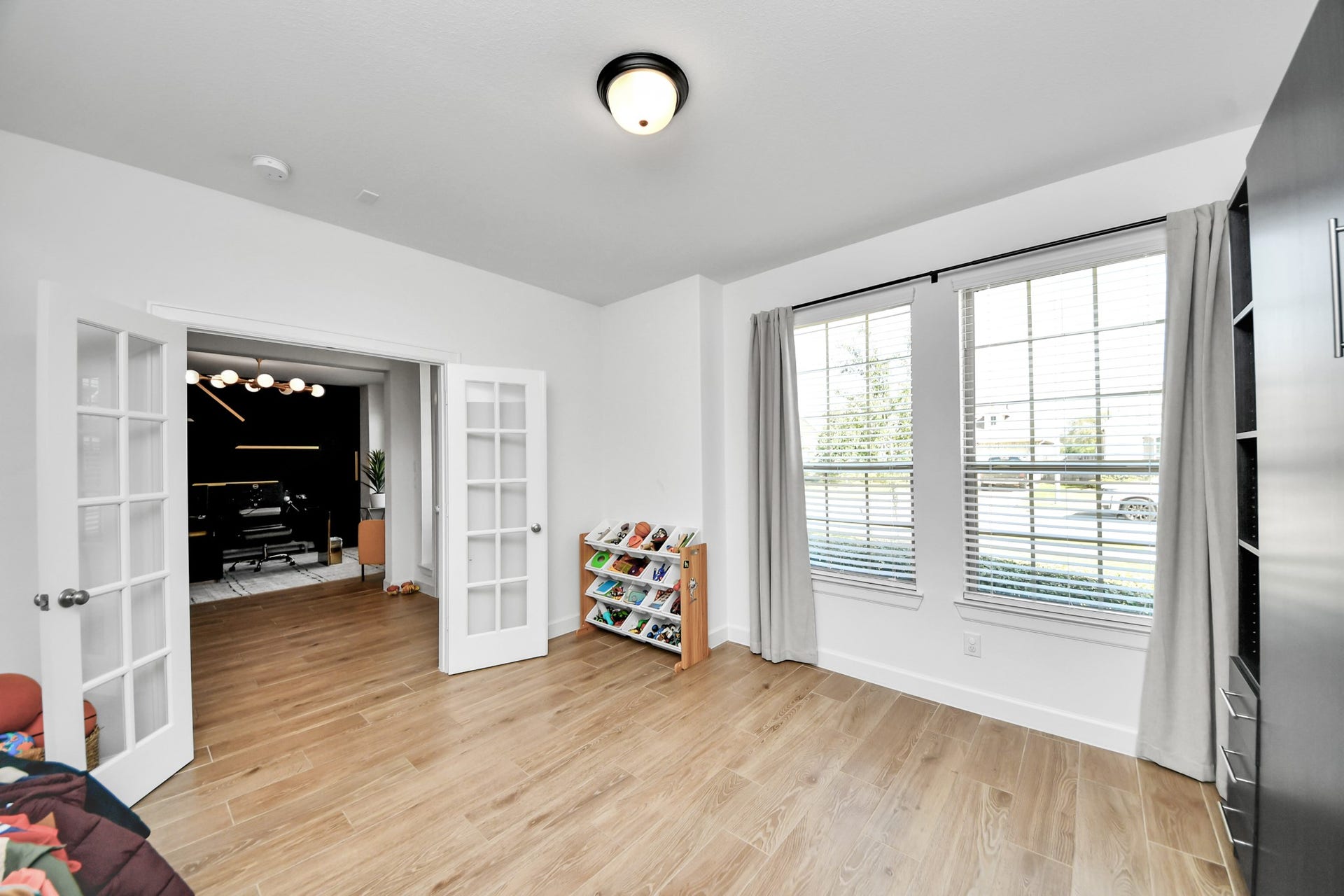 5542 Fairfield Lane, Pasadena, TX 77505 Bright and spacious room with elegant wood flooring, large windows for natural light, and charming French doors leading to an adjacent room, perfect for a home office or play area.