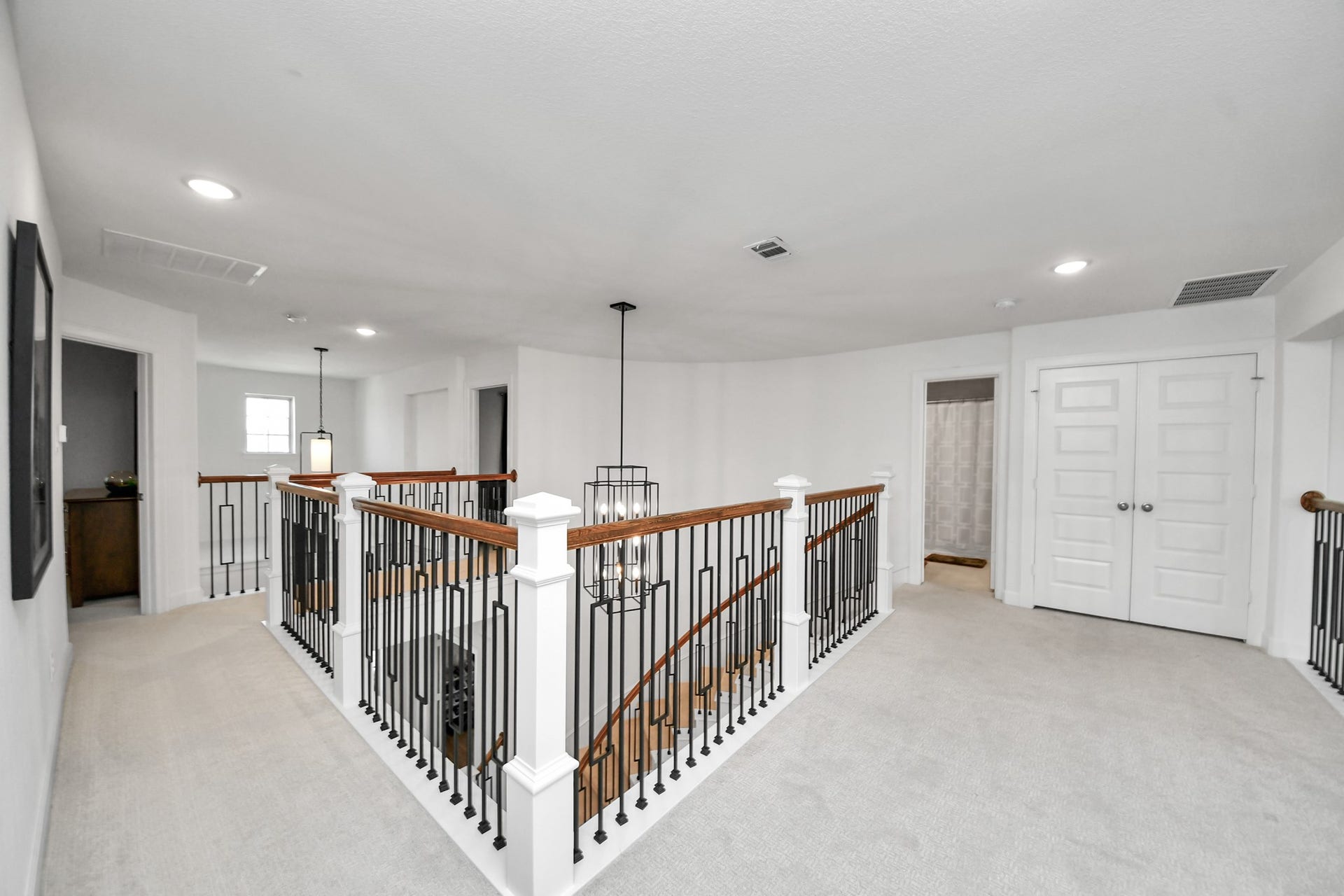 5542 Fairfield Lane, Pasadena, TX 77505 Spacious upstairs hallway with elegant iron railing, modern light fixtures, and plush carpeting.