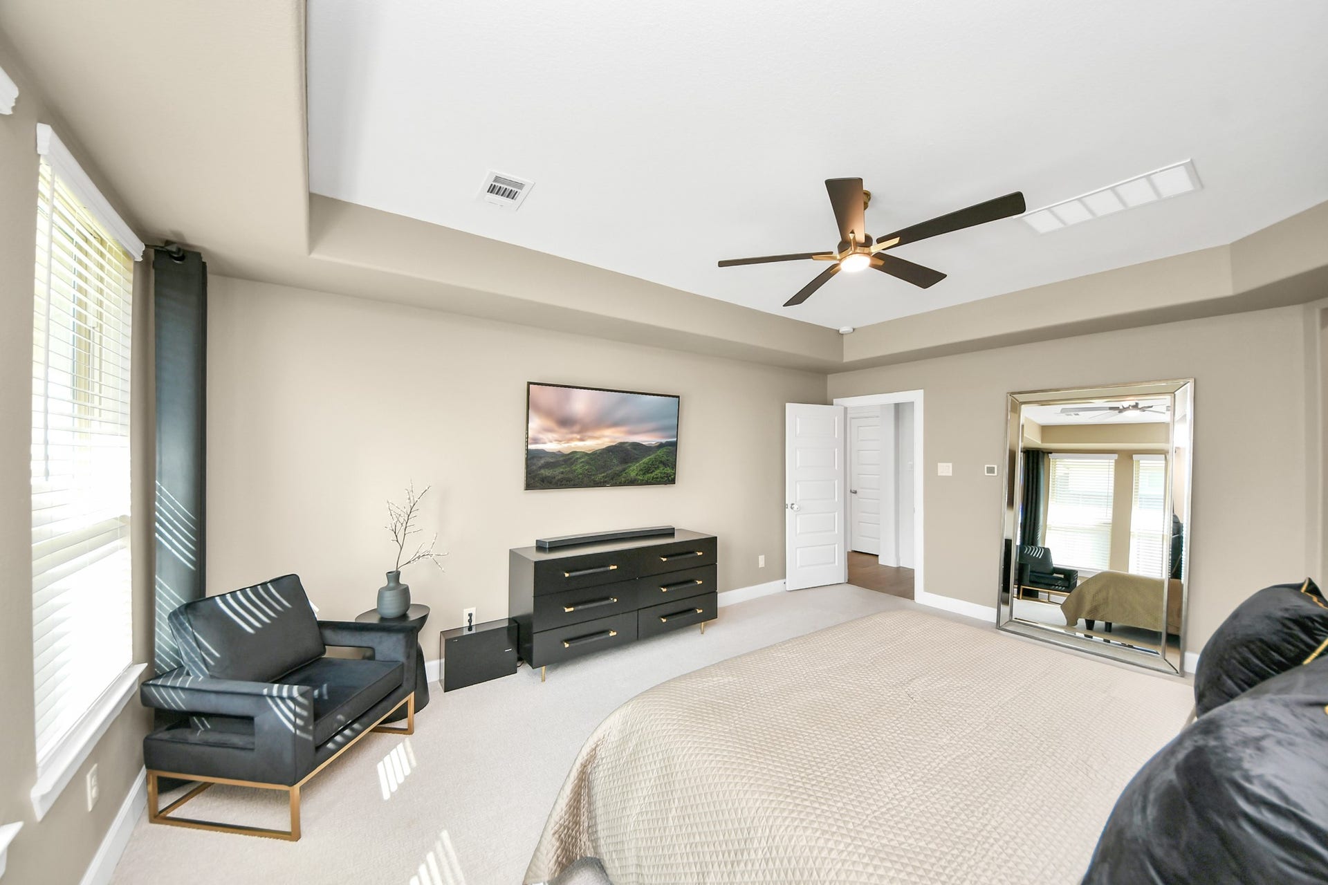 5542 Fairfield Lane, Pasadena, TX 77505 Spacious primary bedroom with abundant natural light, featuring a cozy sitting area, modern ceiling fan, and large mirror to enhance the open feel.