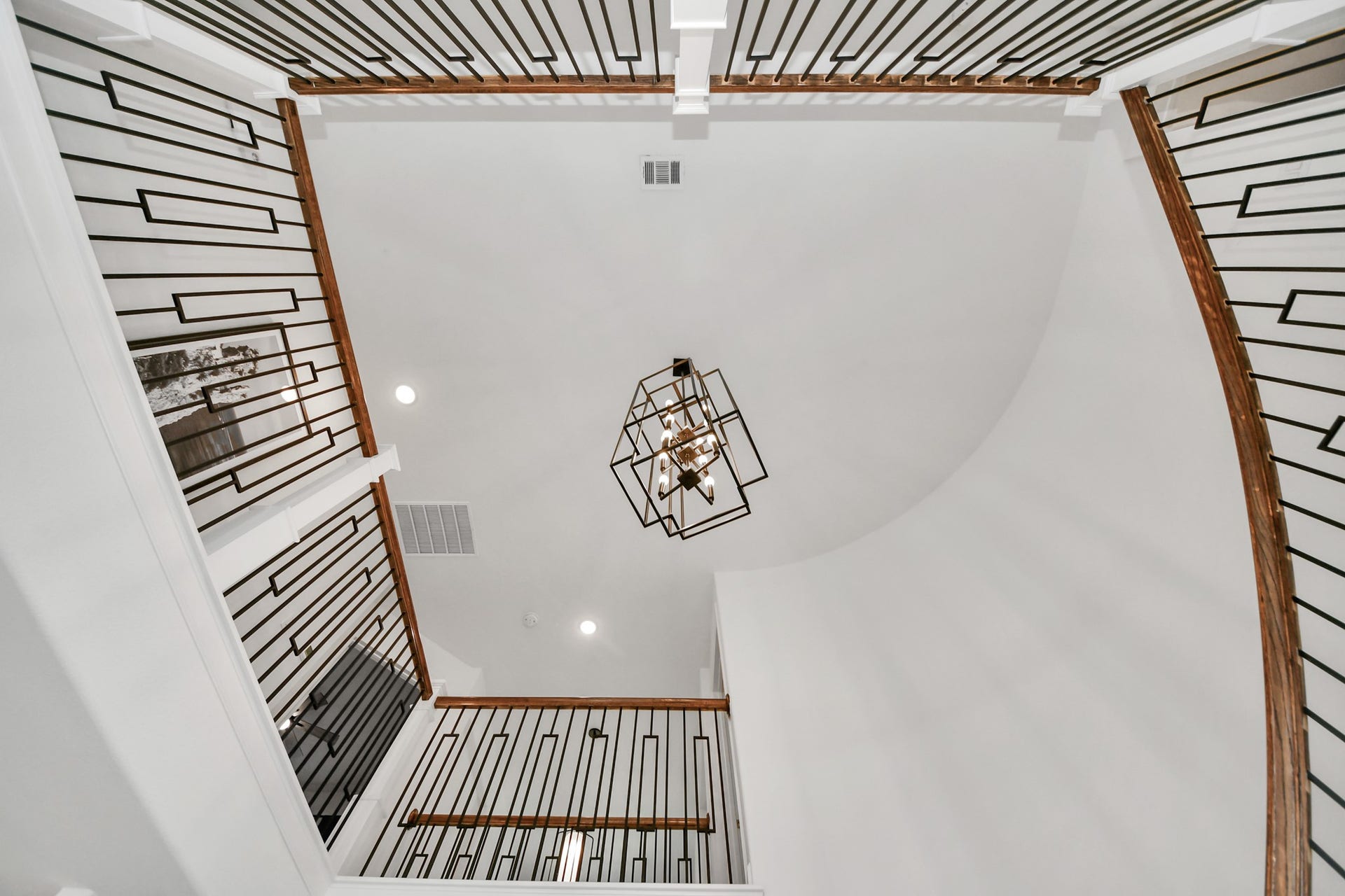 5542 Fairfield Lane, Pasadena, TX 77505 Stunning two-story foyer with elegant geometric railing and a modern chandelier, creating a grand and stylish entrance.