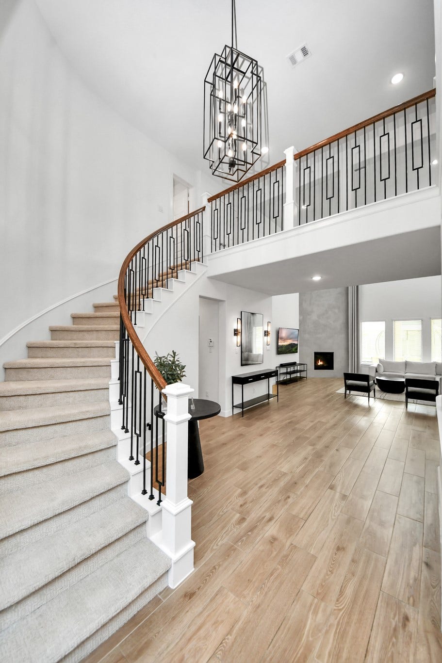 5542 Fairfield Lane, Pasadena, TX 77505 Elegant foyer featuring a sweeping staircase with a modern wrought-iron railing, complemented by a striking chandelier and warm wood flooring.