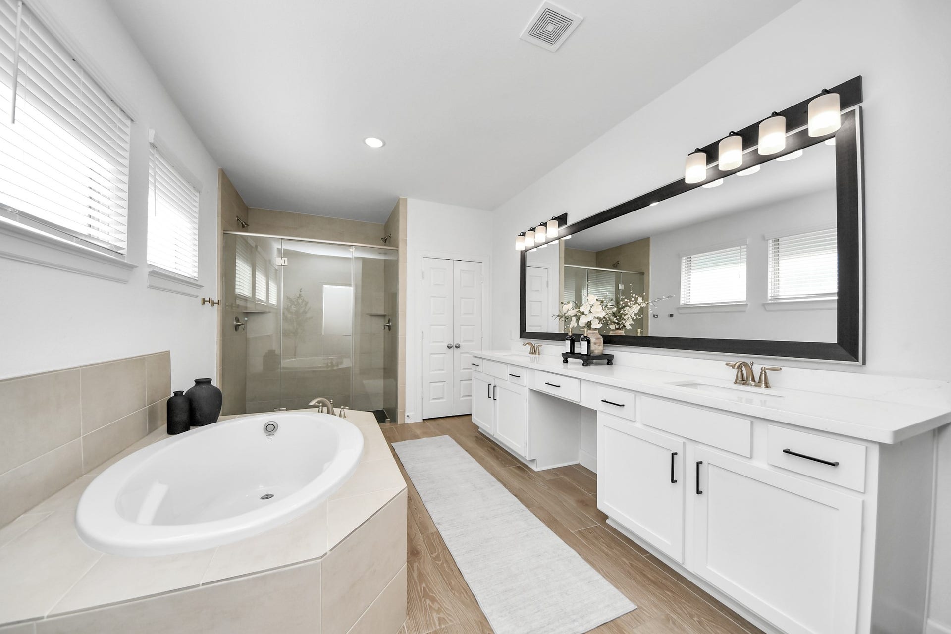 5542 Fairfield Lane, Pasadena, TX 77505 Elegant bathroom featuring a spacious double vanity with modern fixtures, a luxurious soaking tub, and a sleek glass-enclosed shower, all enhanced by abundant natural light.