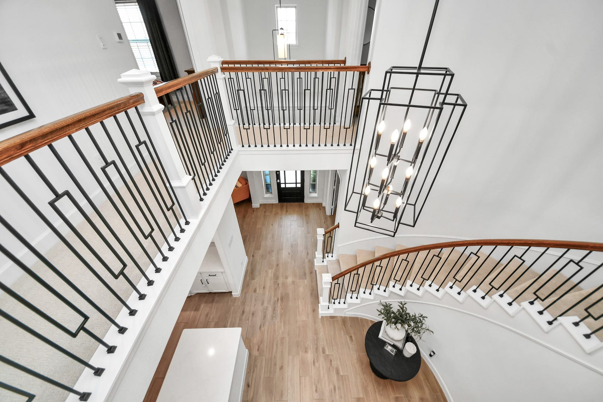 5542 Fairfield Lane, Pasadena, TX 77505 A stunning curved staircase with elegant iron railings and a striking modern chandelier highlights this foyer, offering a grand entrance with beautiful wood flooring.