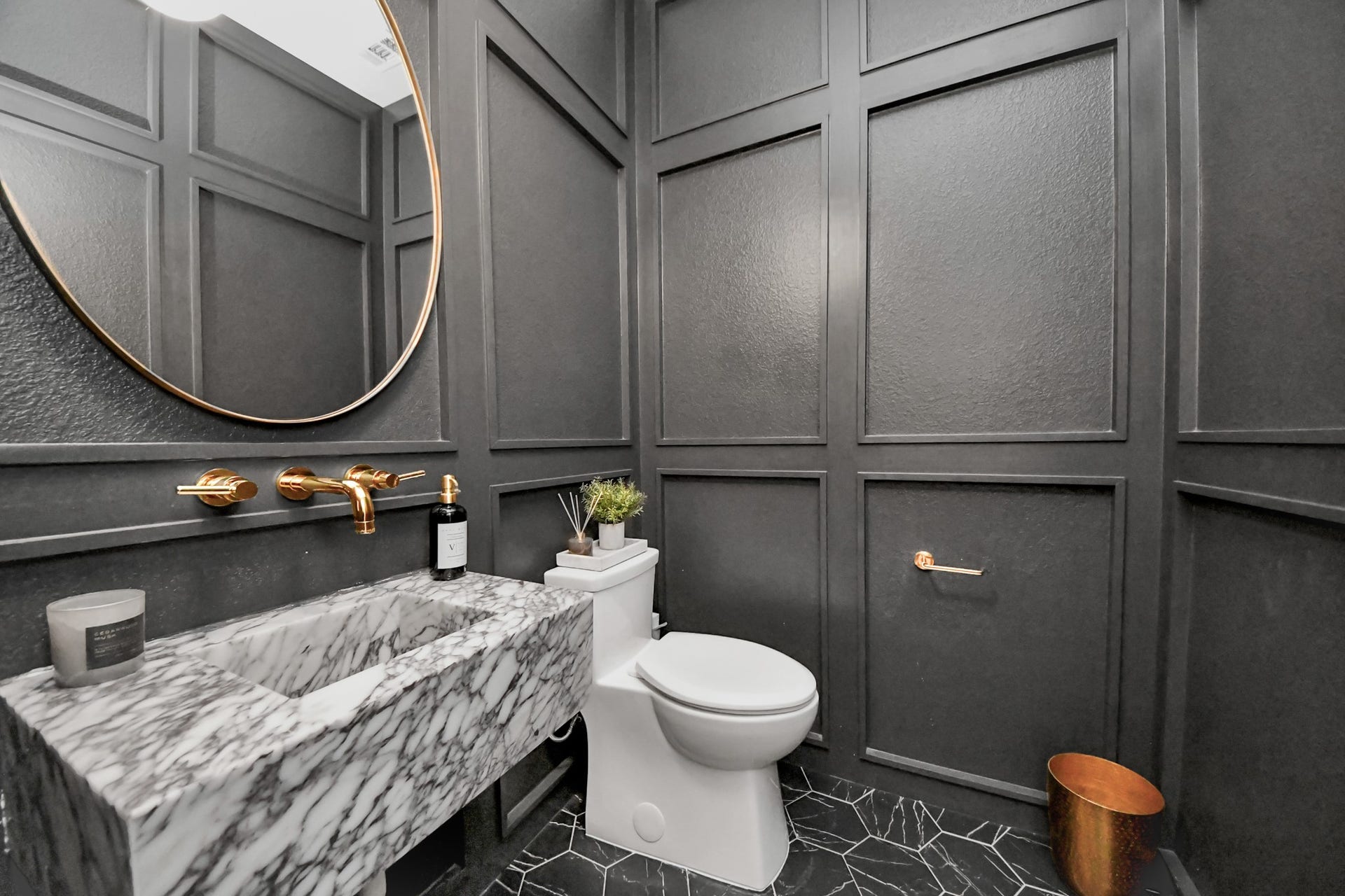5542 Fairfield Lane, Pasadena, TX 77505 Elegant powder room featuring dark paneled walls, a striking Calacatta Viola marble floating sink, and gold accents, offering a sophisticated and modern touch.