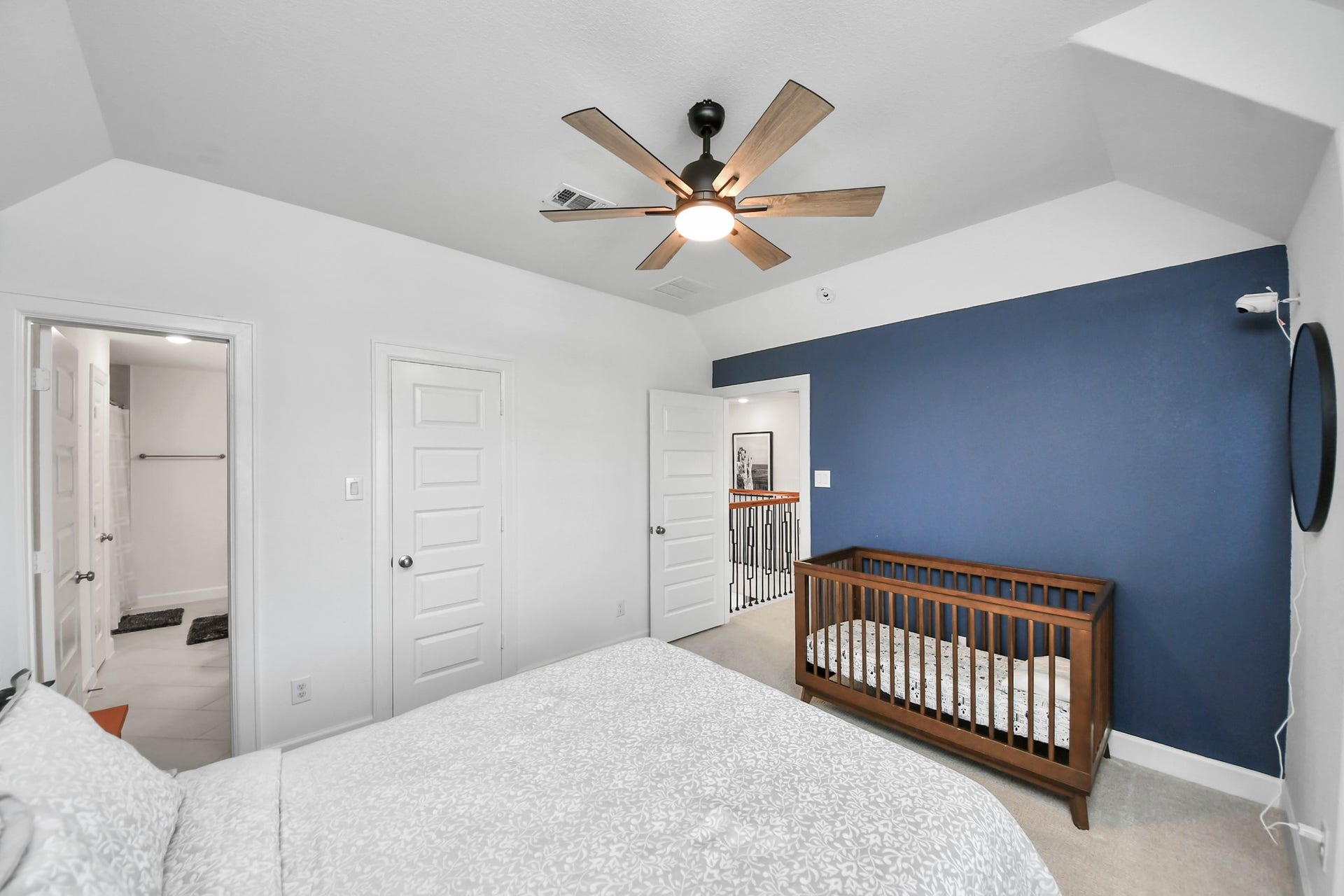 5542 Fairfield Lane, Pasadena, TX 77505 Charming bedroom featuring a cozy crib, elegant blue accent wall, and modern ceiling fan, with convenient access to an en-suite bathroom.