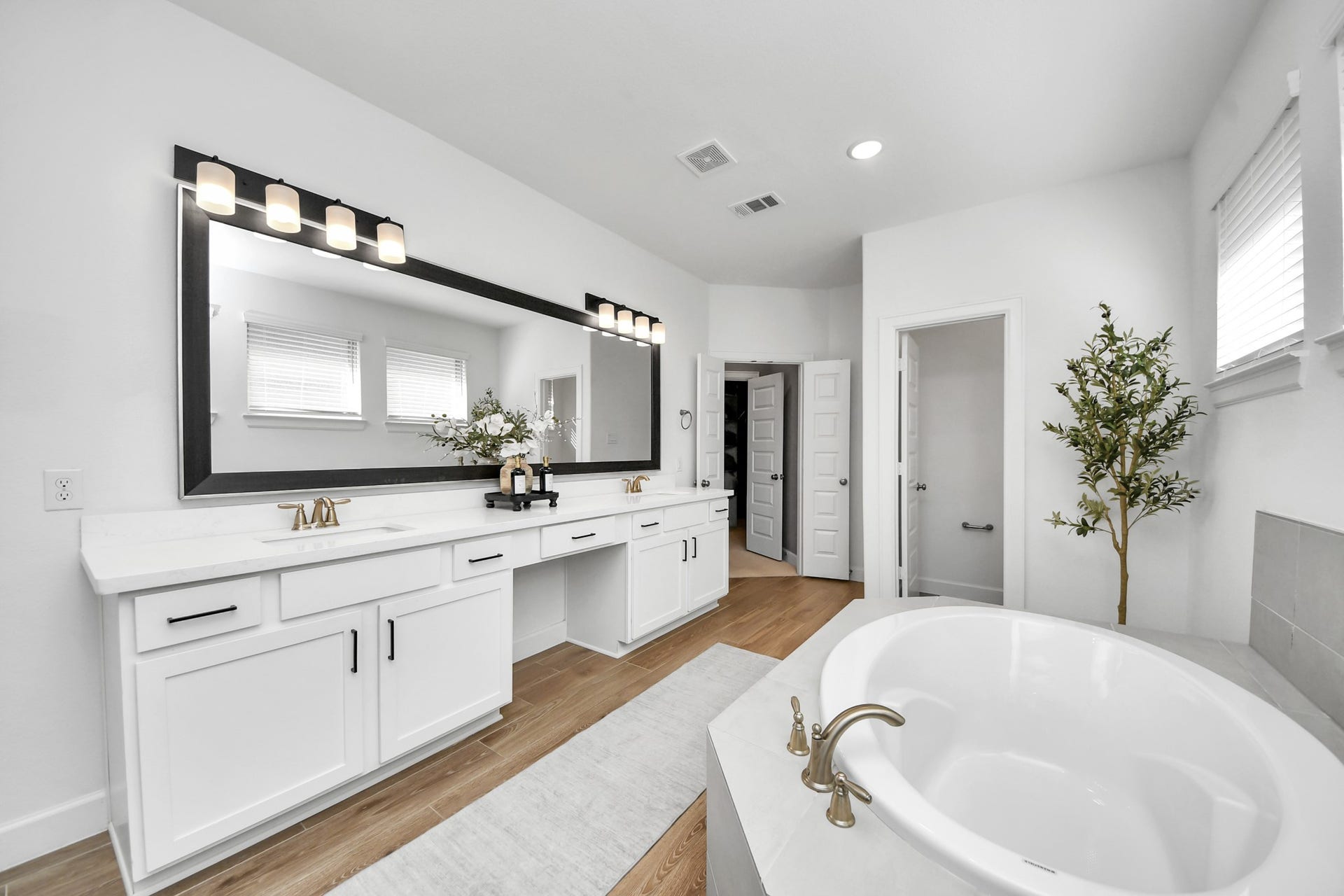 5542 Fairfield Lane, Pasadena, TX 77505 Spacious and elegant primary bathroom featuring a double vanity with sleek fixtures, a large mirror, and a luxurious soaking tub set against a backdrop of neutral tones and natural light.