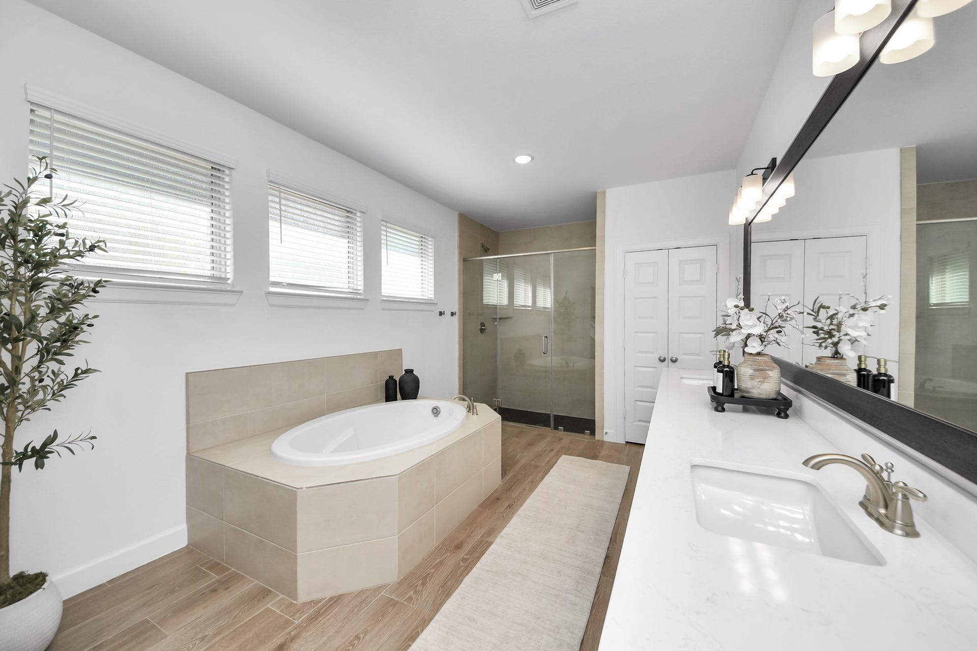 5542 Fairfield Lane, Pasadena, TX 77505 Luxurious bathroom featuring a spacious soaking tub, elegant double vanity with modern fixtures, and a sleek glass-enclosed shower, all enhanced by natural light and tasteful decor.