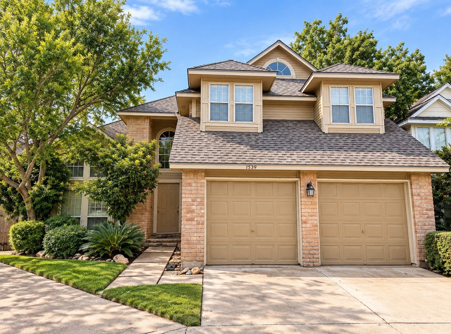 Charming two-story home with a two-car garage and mature landscaping.
