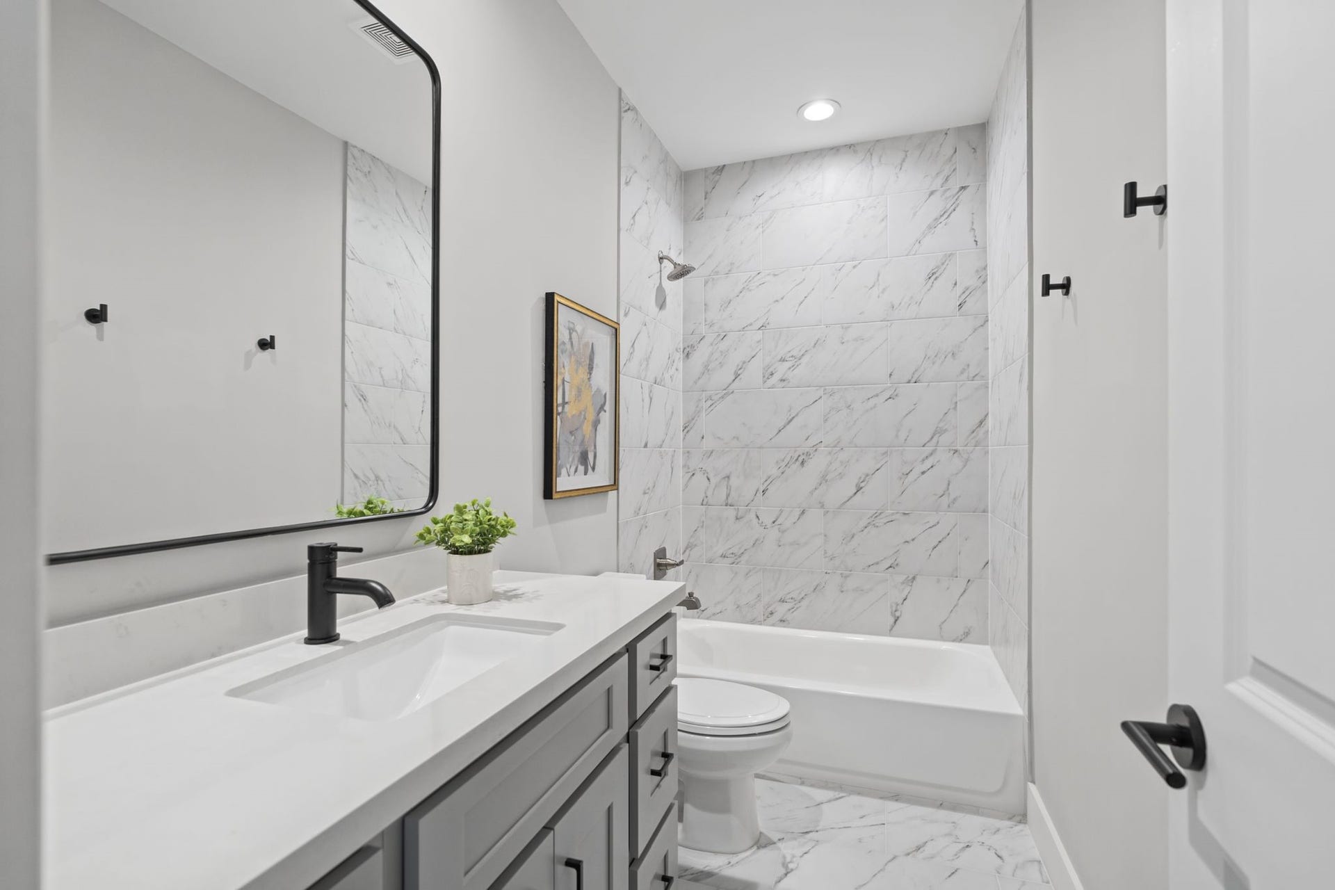 1538 Vermont Street, #A, Houston, TX 77006 Contemporary fixtures, a streamlined vanity, and elegant marble-look tile create a fresh, timeless finish in the secondary bath.