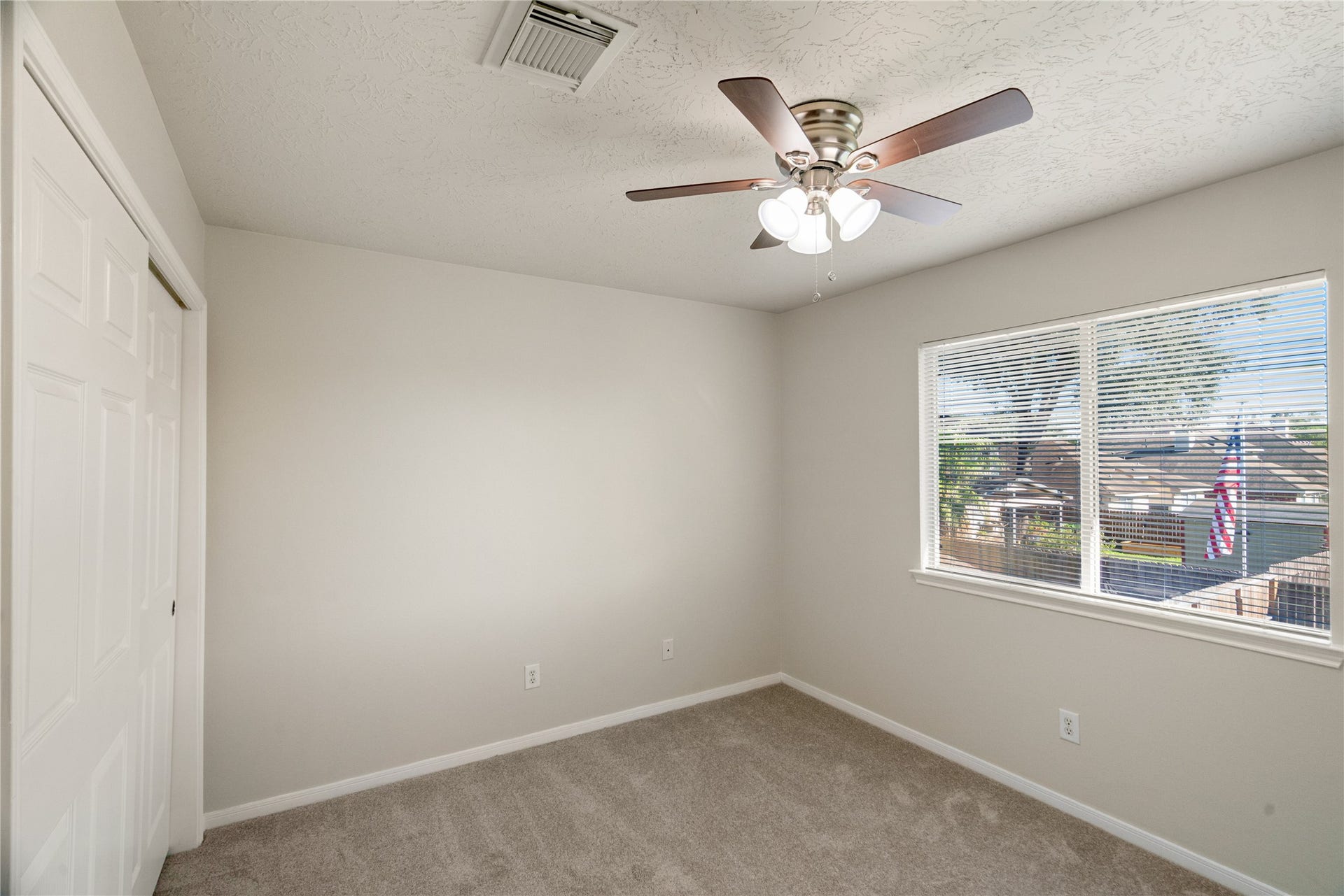 This spacious secondary bedroom offers ample natural light, plush carpeting, and neutral paint tones, making it a versatile space perfect for a guest room, home office, or comfortable bedroom retreat for family members.