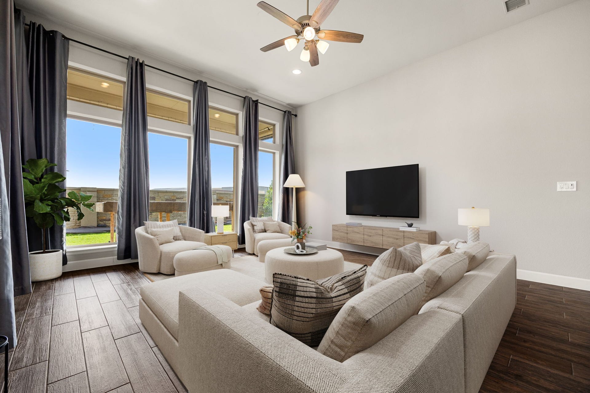 Additional view of this magnificent family room showcasing the sheer volume of the space, anchored by towering 13-foot ceilings and a center-mounted ceiling fan for optimal comfort. The spectacular wall of floor-to-ceiling windows floods every corner with natural light, offering plenty of space to arrange plenty of seating and entertainment centers without ever feeling crowded. *Virtually Staged