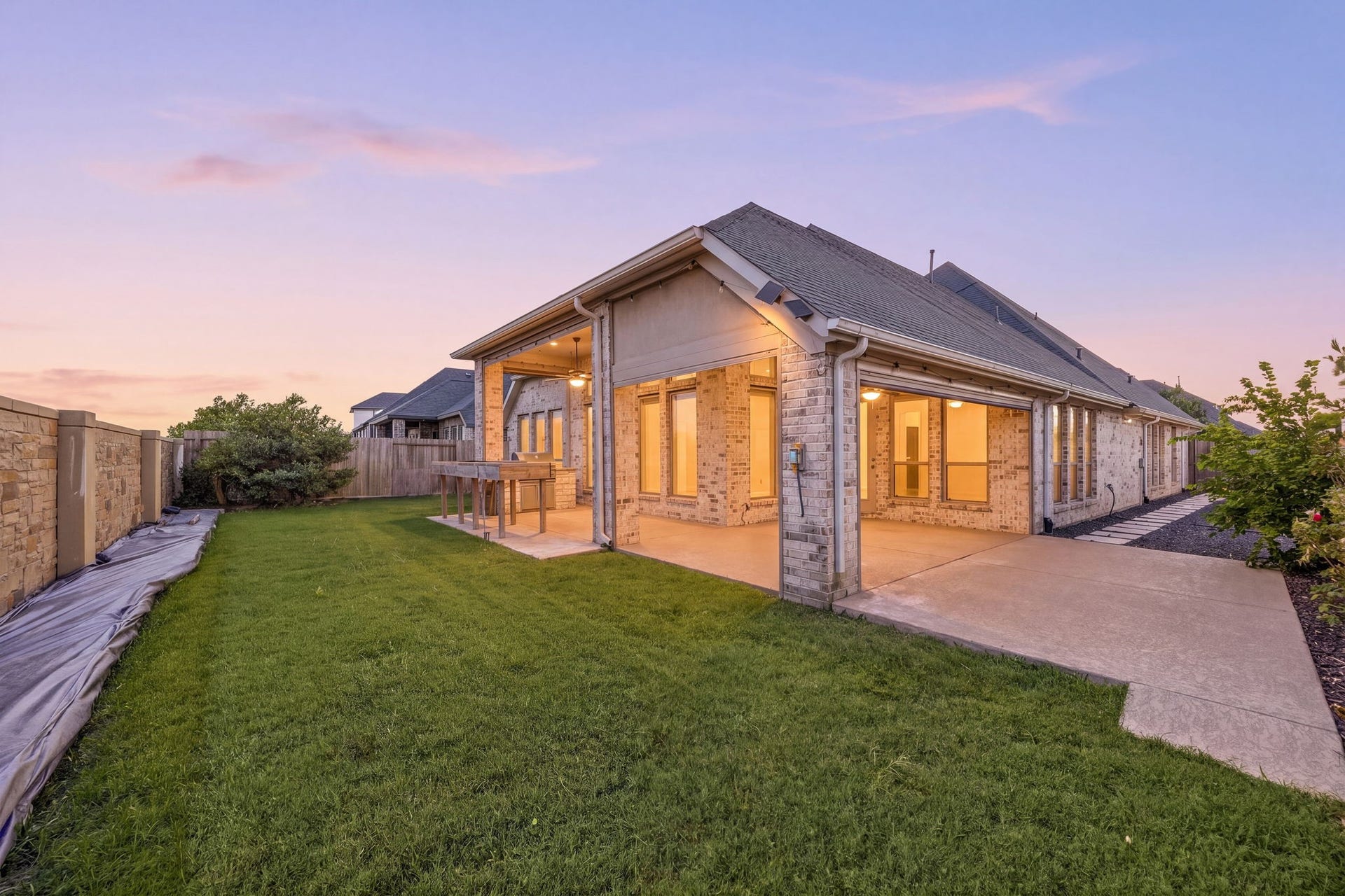 This home's impressive corner lot scale is beautifully framed by premium soffit downlighting, a sprawling green lawn, and the custom stone privacy wall ensuring quiet seclusion.