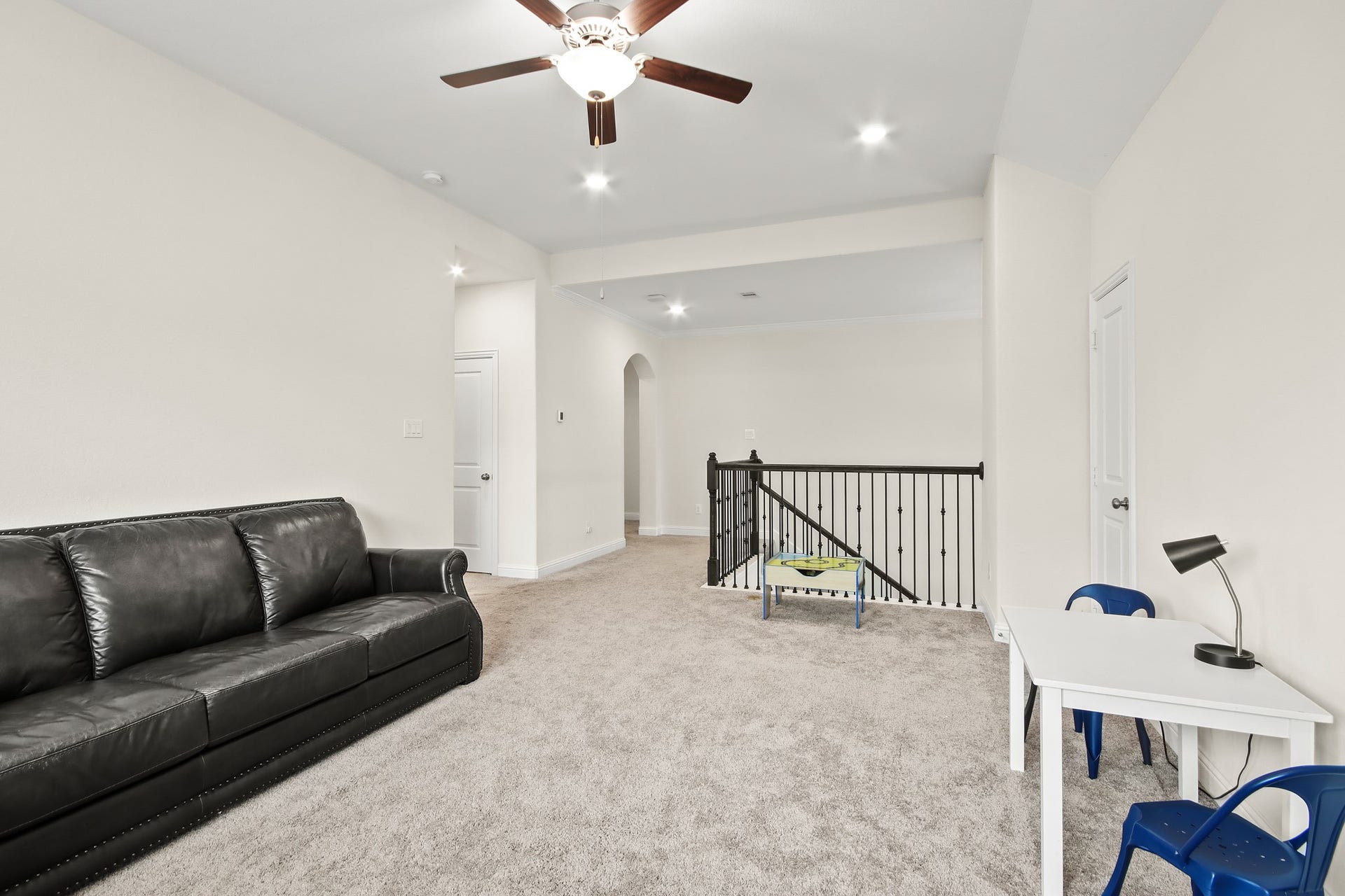 Upstairs spacious game room with neutral carpet, ceiling fan and walk in Texas basement with lots of storage space.