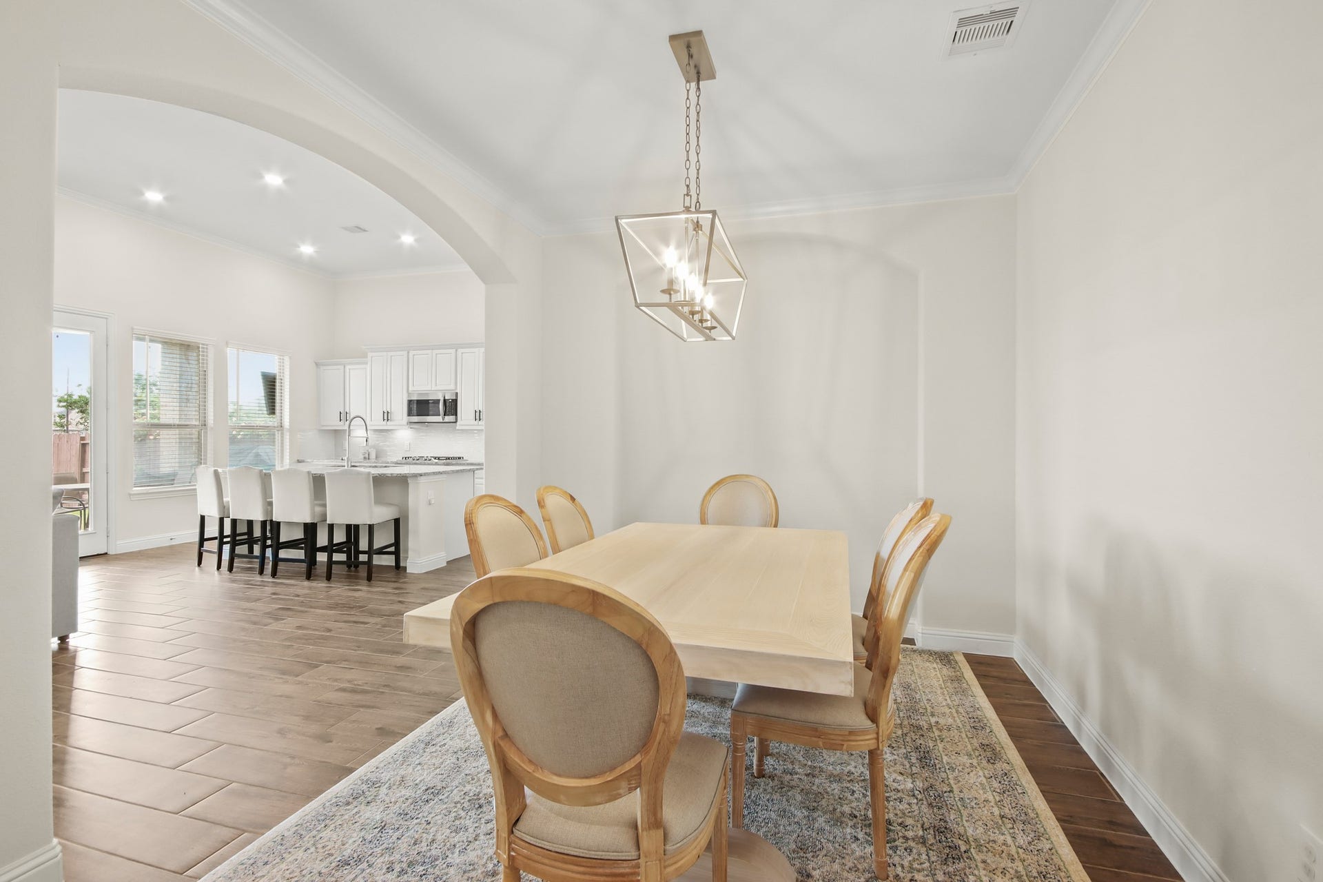 Elegant formal dining room with wood tile flooring, crown molding, arched accents and