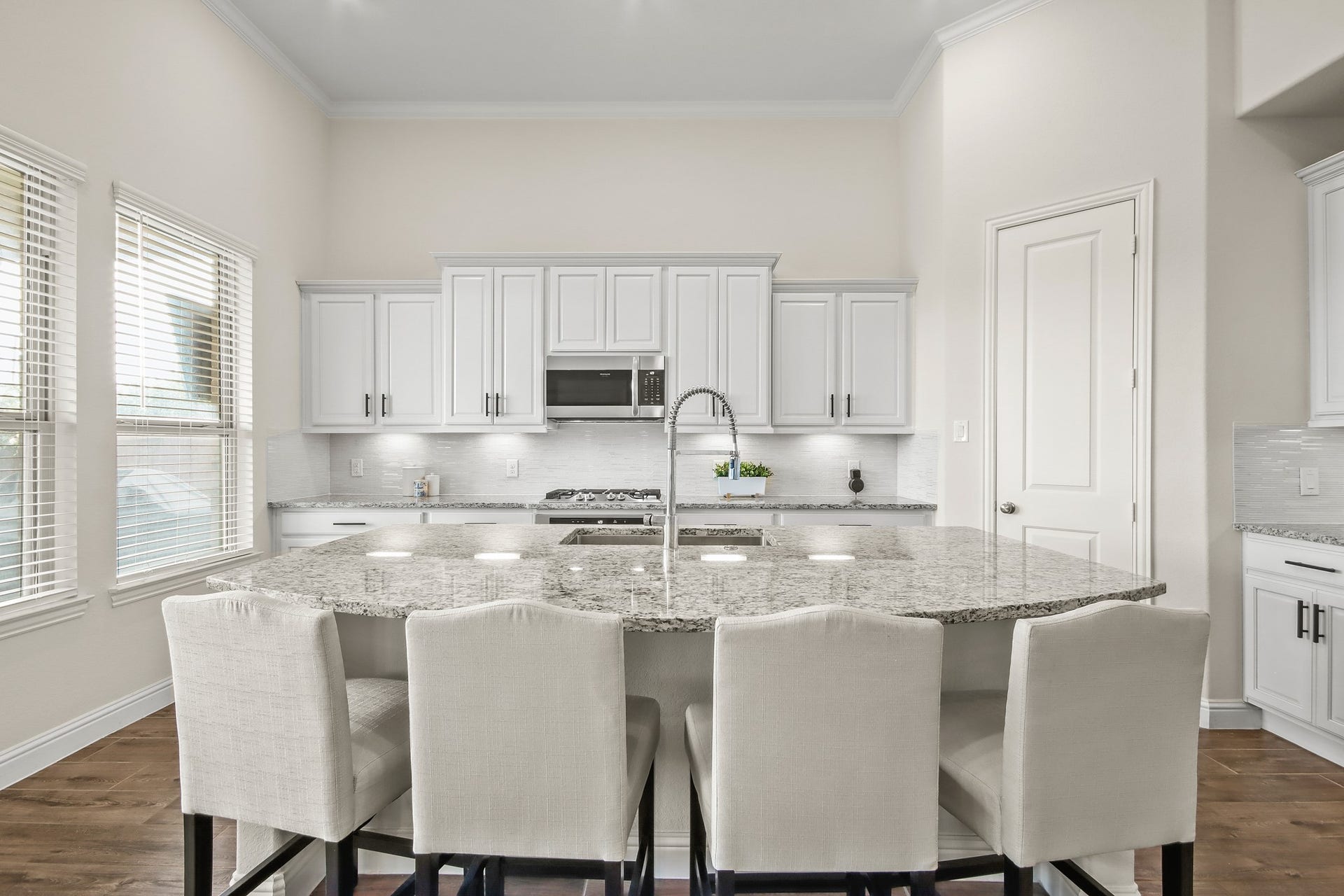 Light and bright kitchen with upgraded white cabinets, upgraded neutral back splash, hardware and desirable countertops.