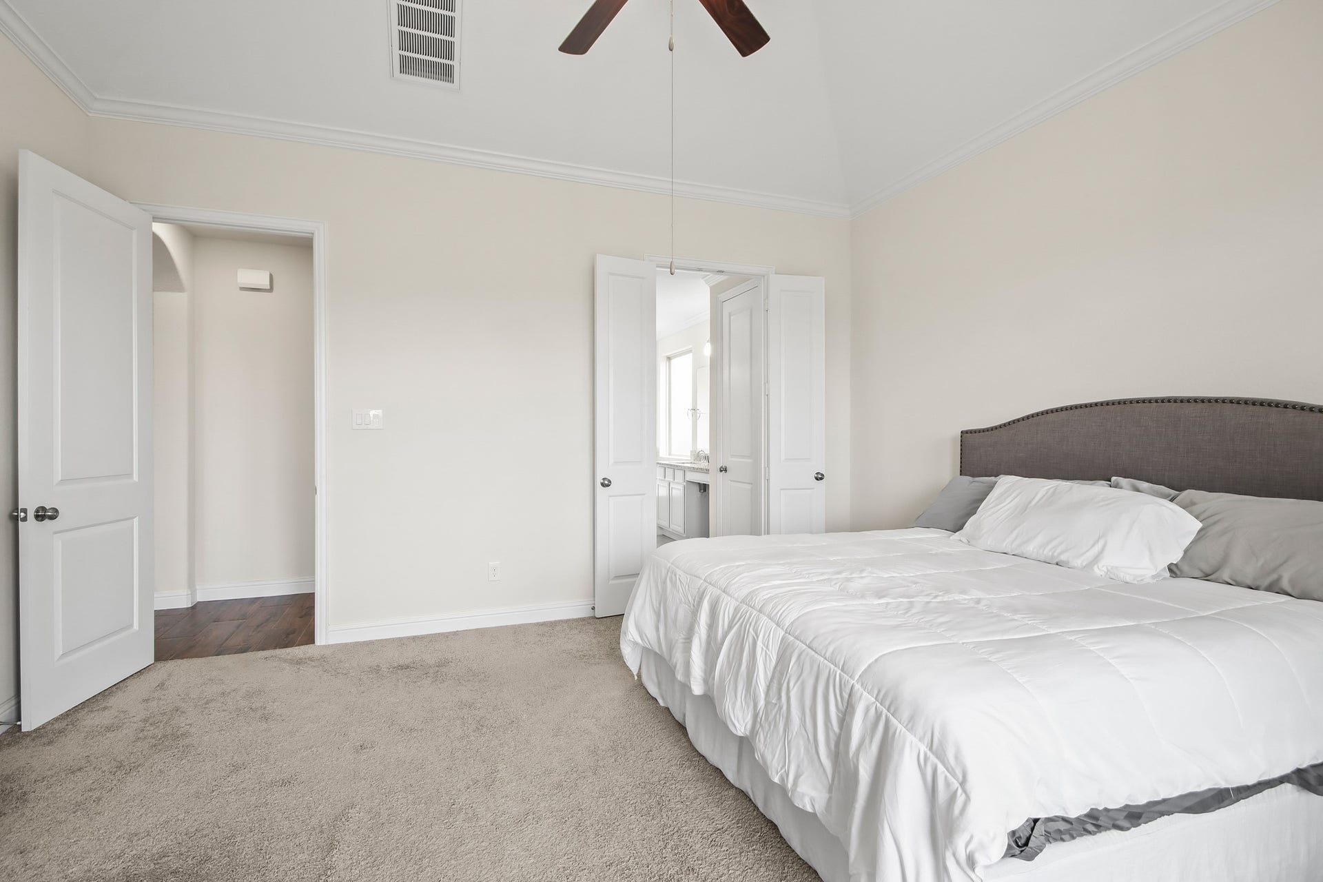 Primary bedroom with neutral carpet, ceiling fan and large walk in closet.