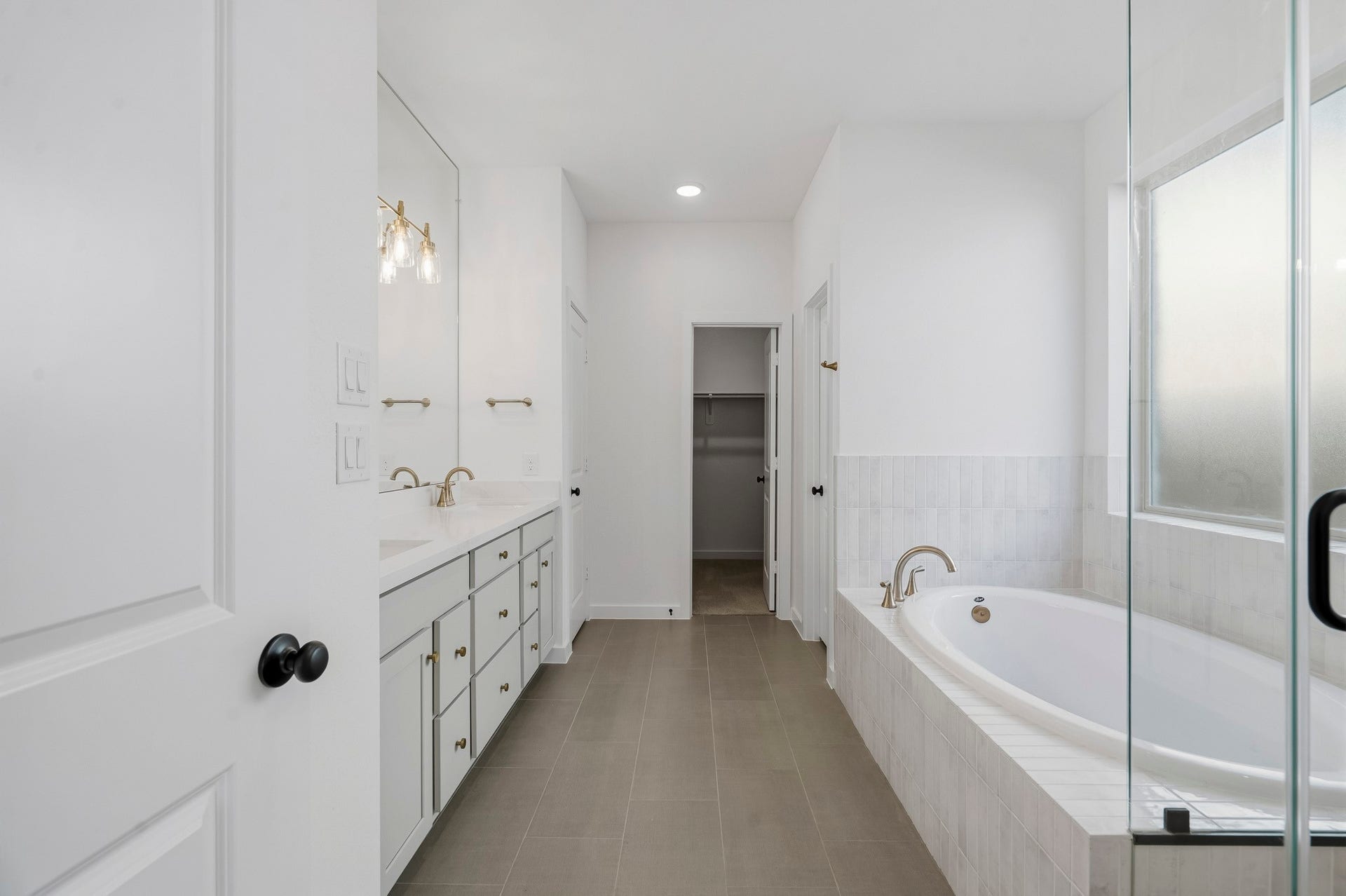 4522 Sunny Hazel Lane, Fulshear, TX 77441 Spa-inspired primary bath featuring a soaking tub, glass-enclosed shower, dual vanities, and refined brass accents.