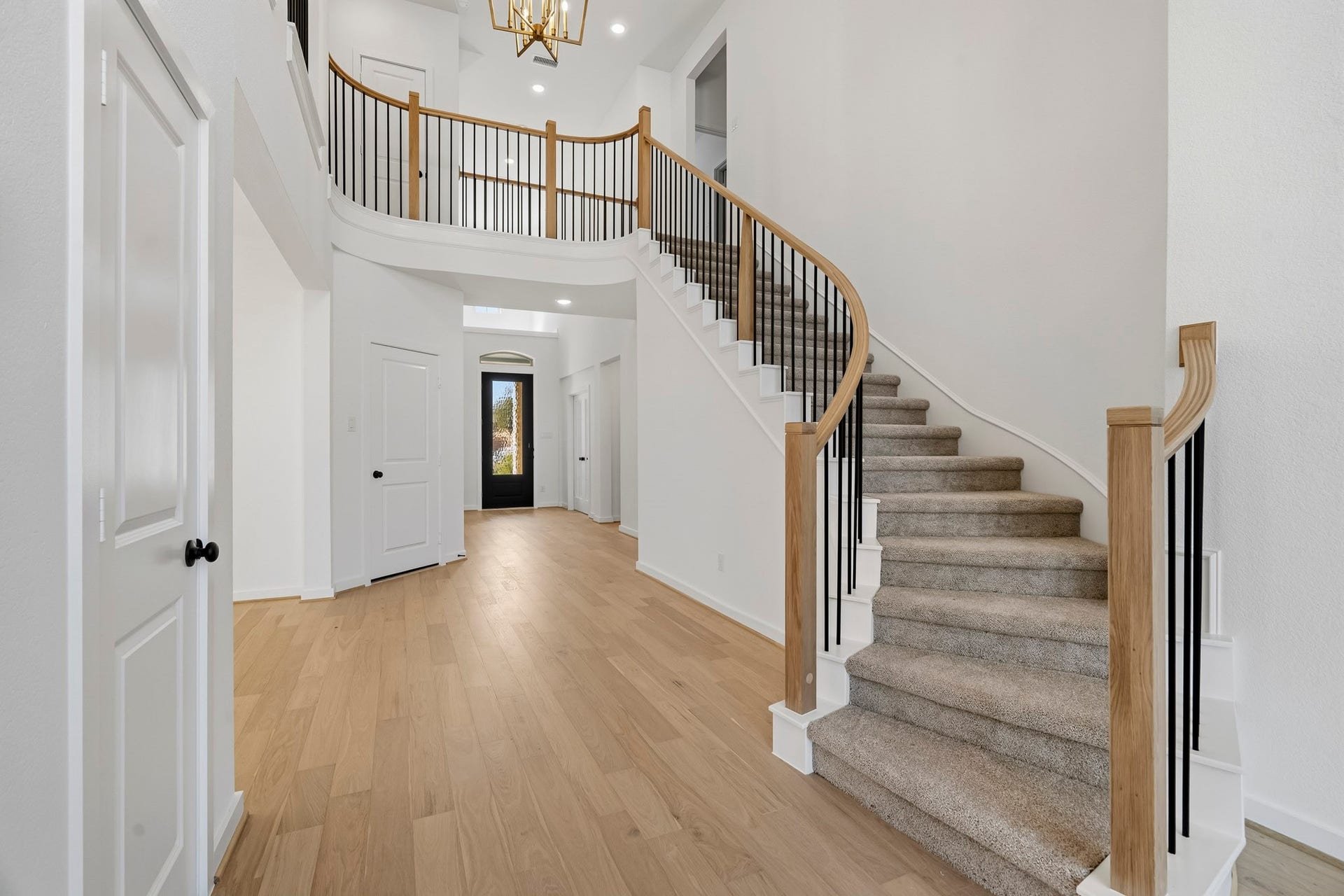 4522 Sunny Hazel Lane, Fulshear, TX 77441 Statement curved staircase with natural wood accents, sleek iron balusters, and an elegant architectural design.