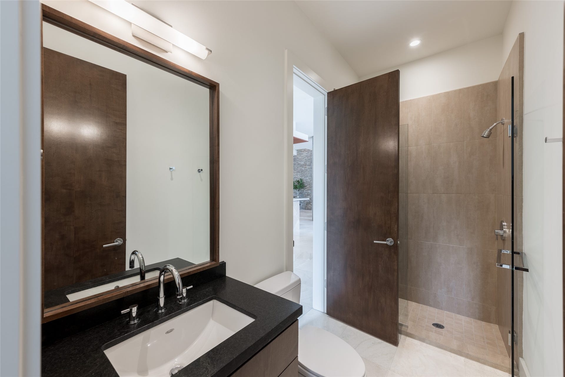 309 Glenwood Drive, Houston, TX 77007 One of two full bathrooms on the first floor, this space also serves as the dedicated pool bath with convenient access from the outdoor living area. A walk-in shower allows guests to transition directly from the pool without moving through the main living spaces.