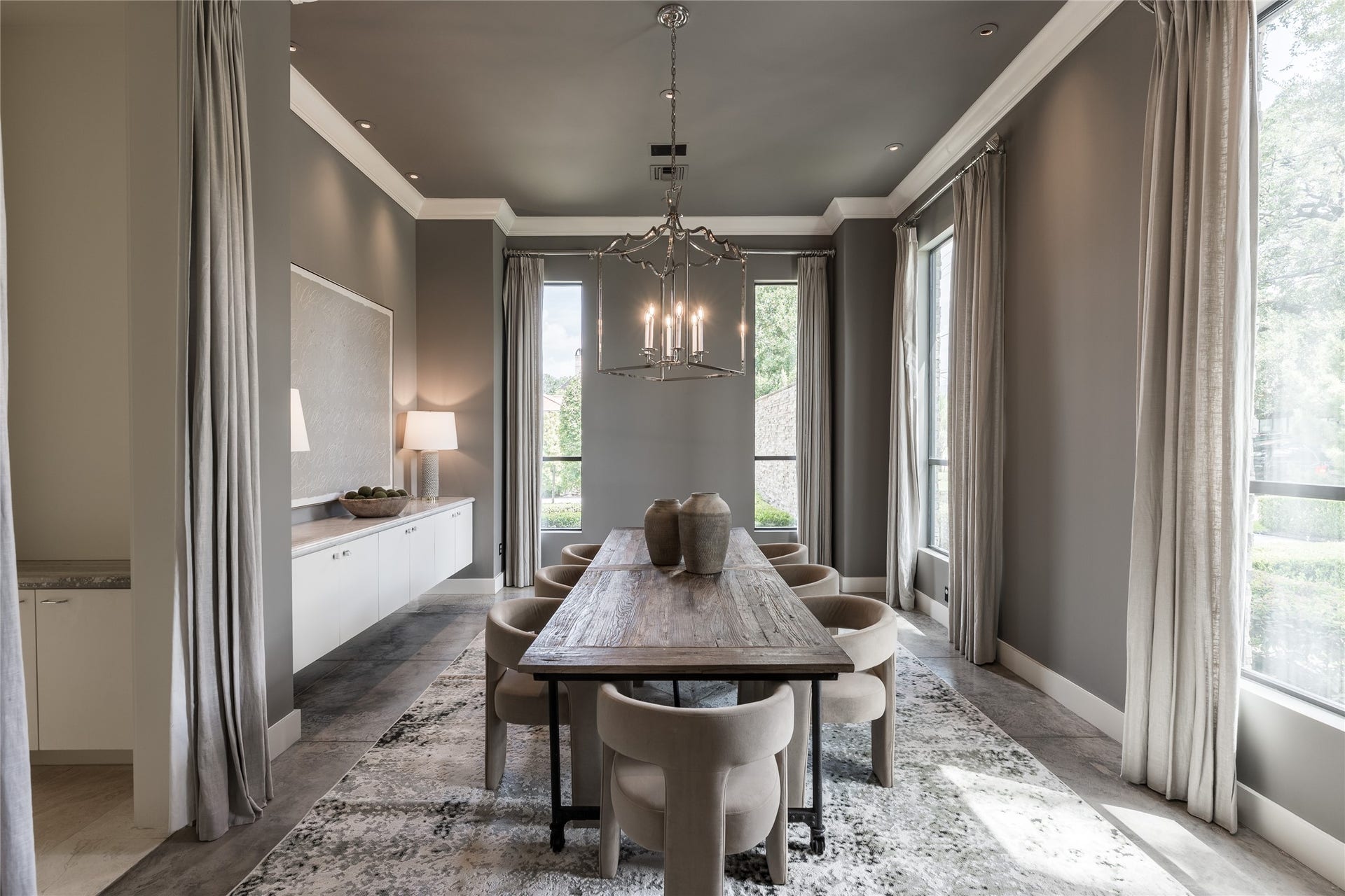 309 Glenwood Drive, Houston, TX 77007 The formal dining room unfolds across from the study, framed by floor-to-ceiling windows dressed in custom curtains that soften the natural light. A sculptural chandelier anchors the elongated space, creating an elegant setting for intimate dinners or larger gatherings.
