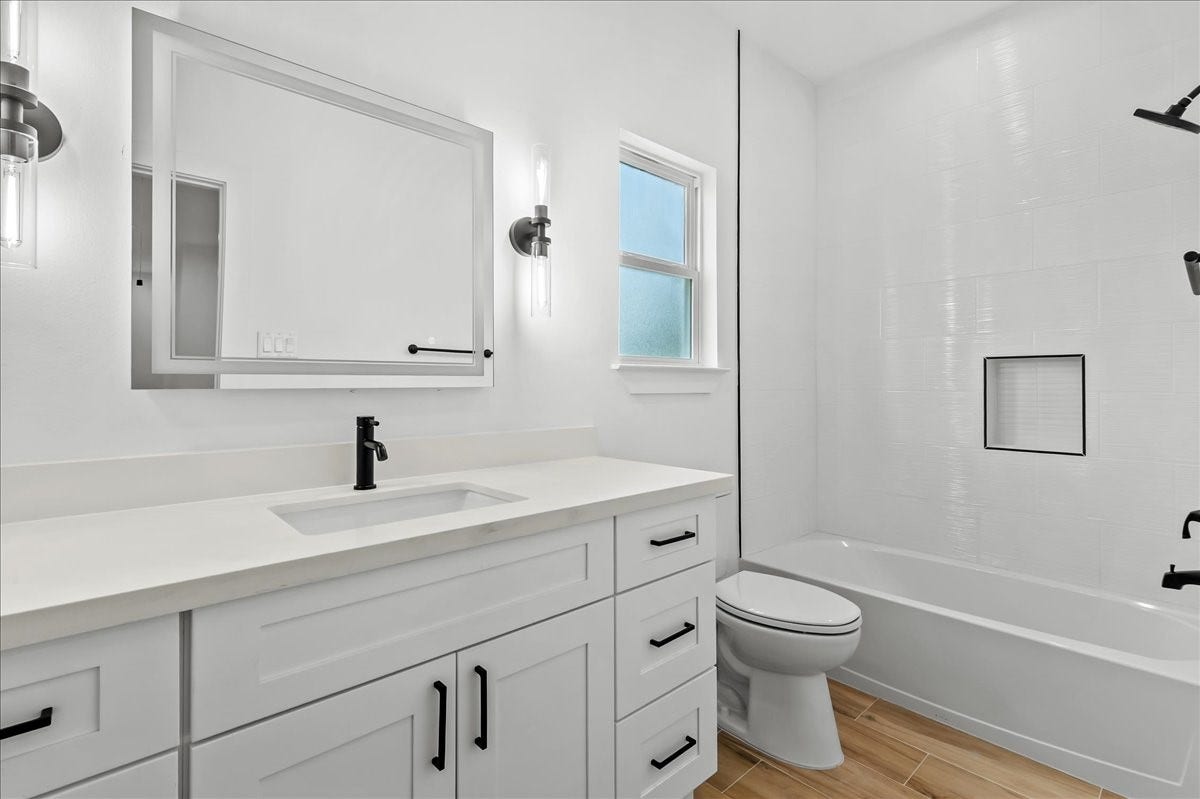 8323 Observatory Street, #A/B, Houston, TX 77088 Unit A - Secondary bathroom features a tub/shower combination accented with elegant black fixtures and a modern LED vanity mirror, creating a stylish and functional space for family and guests.