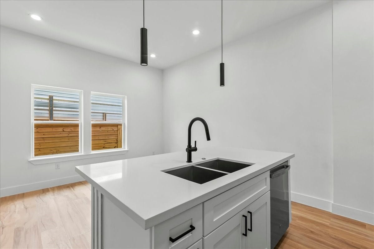 8323 Observatory Street, #A/B, Houston, TX 77088 Unit B - The spacious kitchen island serves as the centerpiece of the home, offering a seamless view of the dining area and large windows that fill the space with natural light.