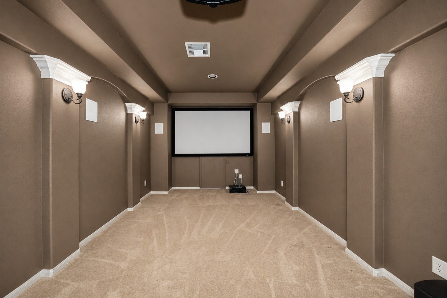 6323 Orange Blossom Lane, Rosenberg, TX 77471 This photo shows a cozy home theater room with a large screen, carpeted flooring, and elegant wall sconces for ambient lighting. The neutral tones create a warm and inviting atmosphere, perfect for movie nights.