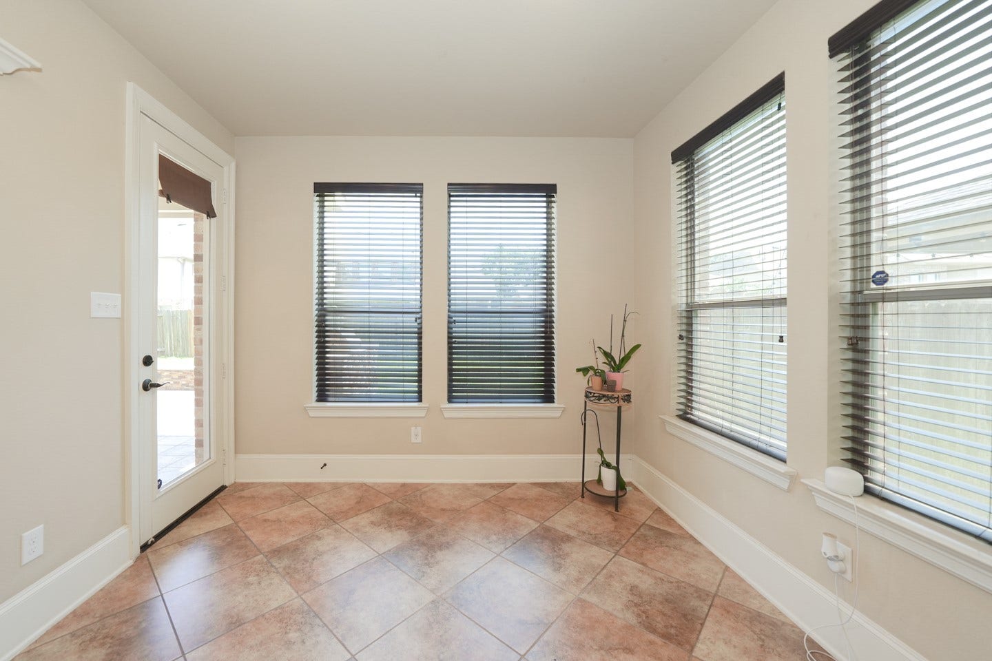 6323 Orange Blossom Lane, Rosenberg, TX 77471 Bright space that extends from the kitchen with large windows featuring blinds, tiled floor, and a door leading outside. Perfect for plants or a cozy reading nook.
