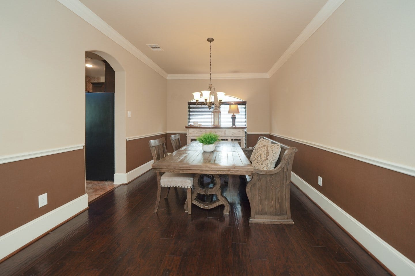 6323 Orange Blossom Lane, Rosenberg, TX 77471 This dining room features elegant wood flooring, and warm two-tone walls with wainscoting. A chandelier adds a touch of sophistication, and an arched entry leads to the adjacent Kitchen entrance.