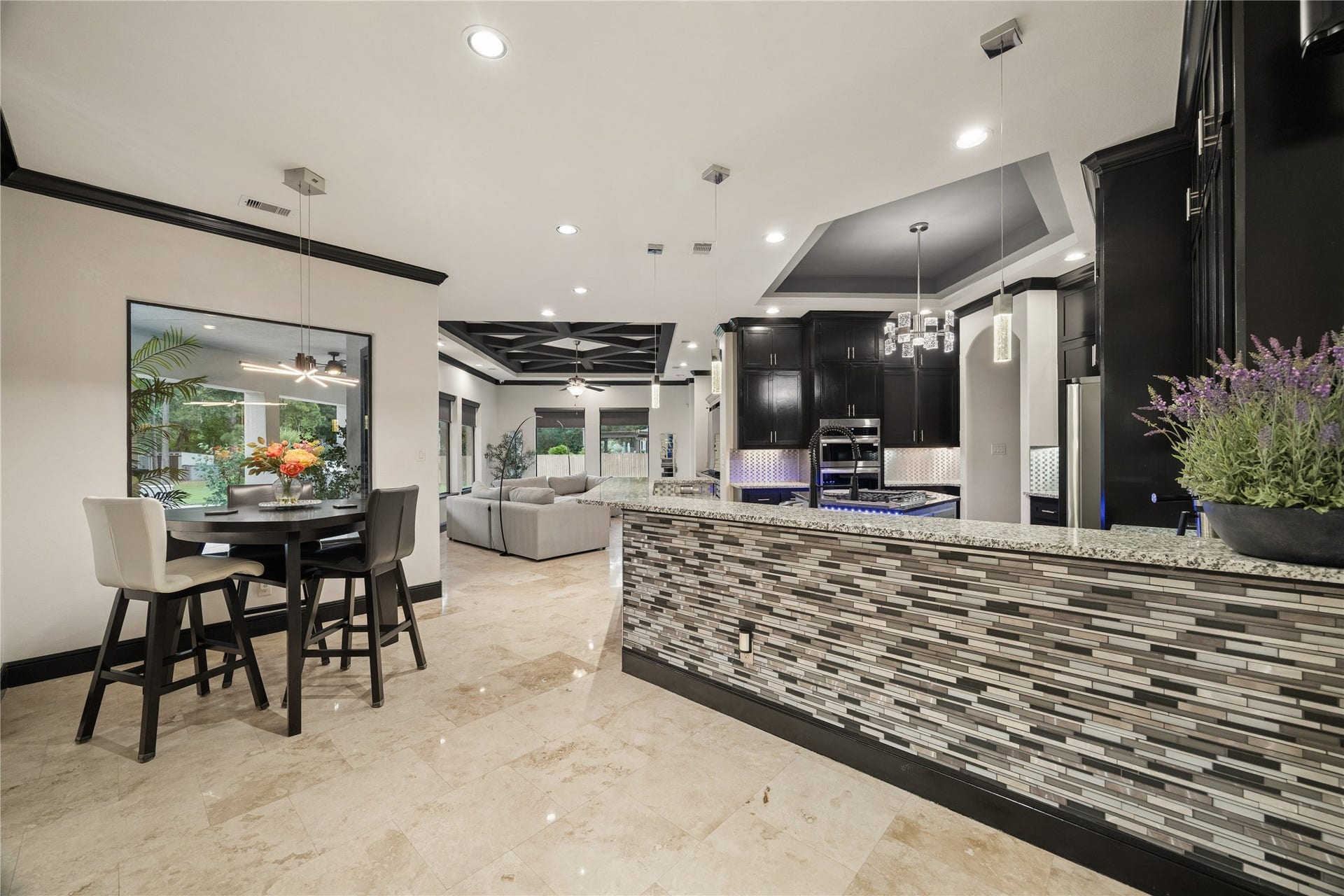 27303 E Benders Landing Boulevard, Spring, TX 77386 Open-concept kitchen with a breakfast nook and spacious breakfast bar with granite countertops, decorative mirrored tile accents, and beautiful pendant lighting.