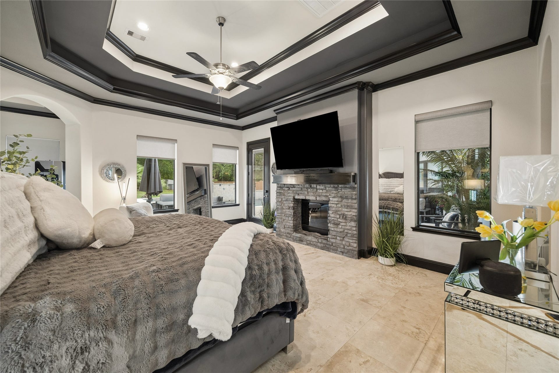 27303 E Benders Landing Boulevard, Spring, TX 77386 Large windows fill the primary suite with natural light, while the double-sided stone fireplace adds warmth and elegance to both the bedroom and covered patio. Private patio access creates a seamless indoor-outdoor retreat.