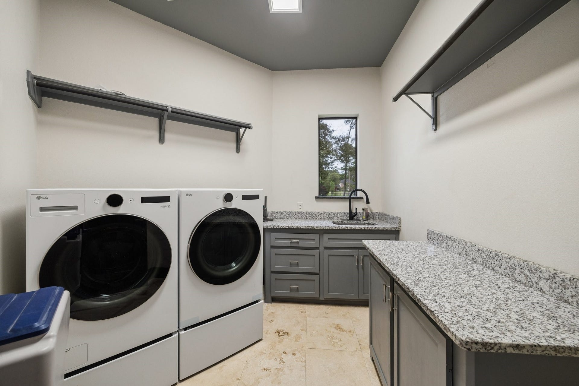 27303 E Benders Landing Boulevard, Spring, TX 77386 Spacious laundry room with utility sink, granite countertops, workspace ideal for folding clothes, cabinetry for additional storage, upper shelving with hanging rods for added convenience and organization.
