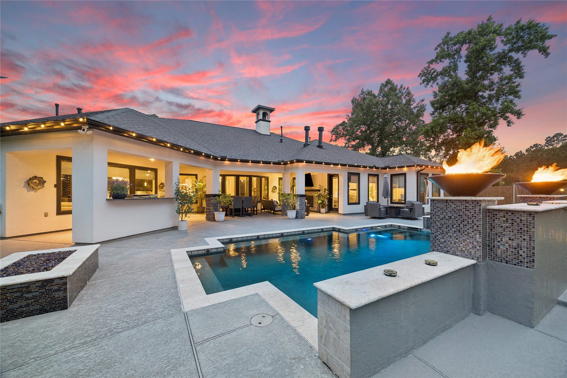 27303 E Benders Landing Boulevard, Spring, TX 77386 This resort-style backyard features a sparkling pool, covered patio with fireplace, elegant fire bowls and spacious outdoor seating areas, creating a private retreat with a warm and inviting ambiance.