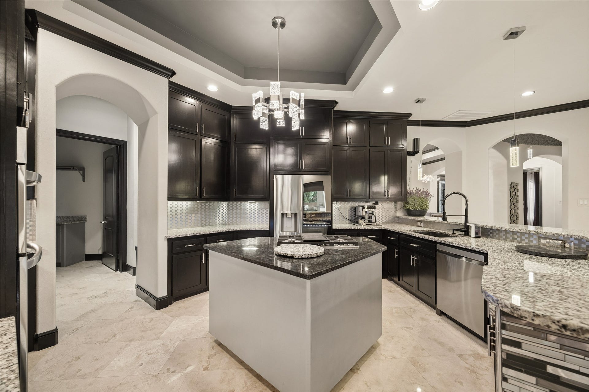 27303 E Benders Landing Boulevard, Spring, TX 77386 Spacious kitchen featuring a large island with cooktop, granite countertops, and a beautiful modern chandelier centered beneath a tray ceiling detail.