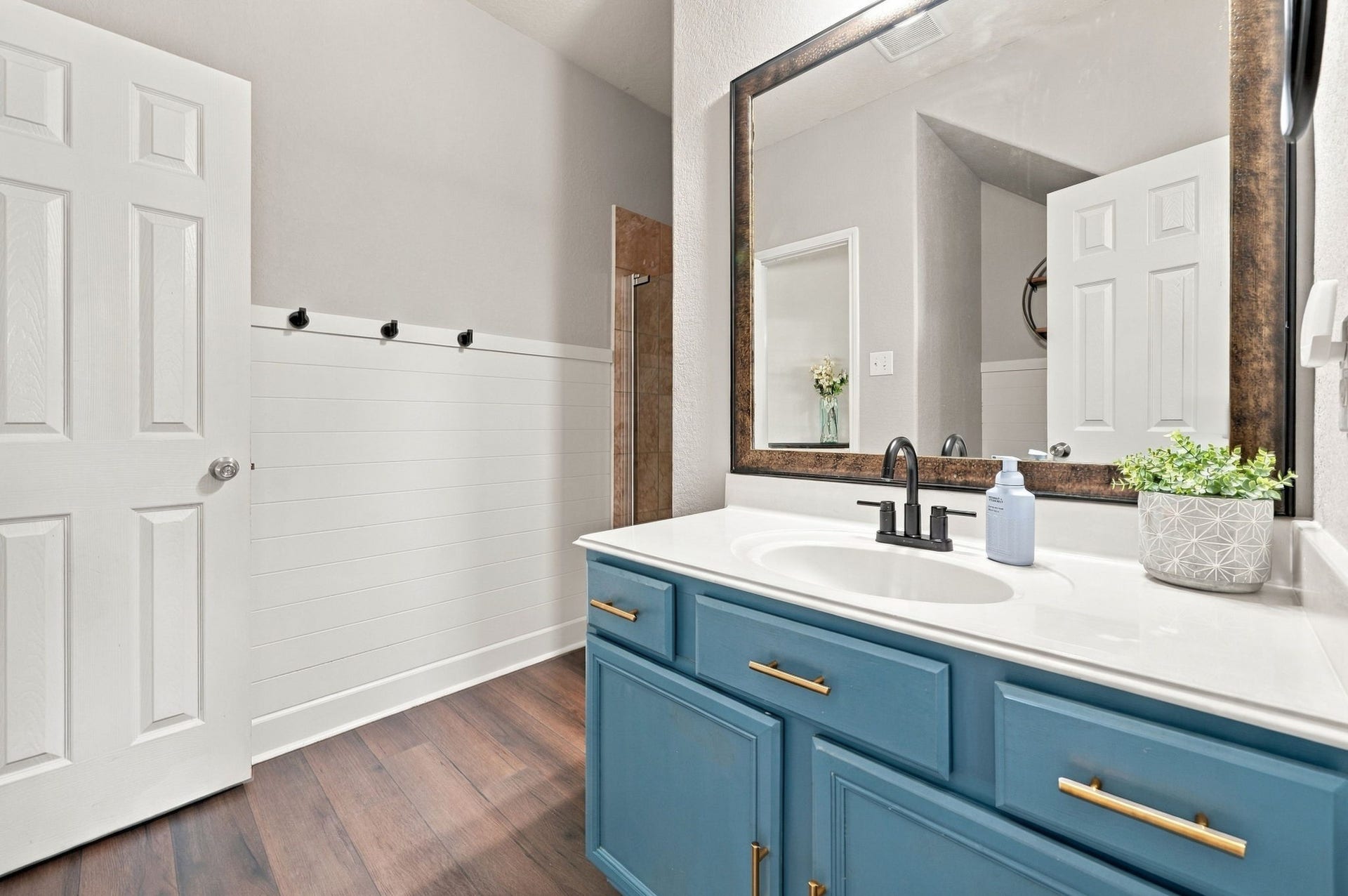 Downstairs Full Bath: Stylish full bath features a distinctive blue vanity with gold-tone hardware, generous counter space and adjacent shower.