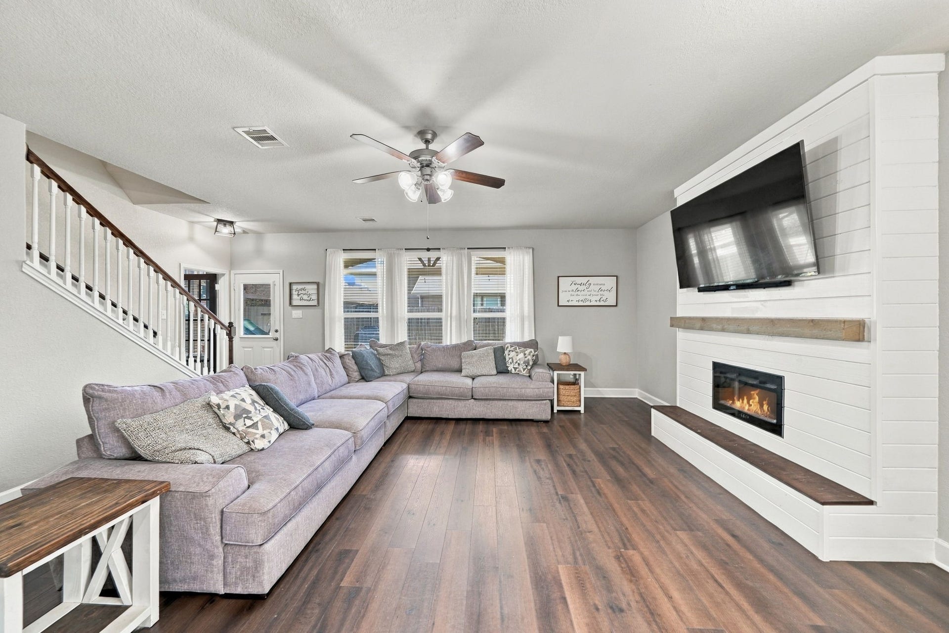 Living Room: Spacious living room filled with natural light and anchored by a striking fireplace feature wall, complemented by warm laminate flooring.