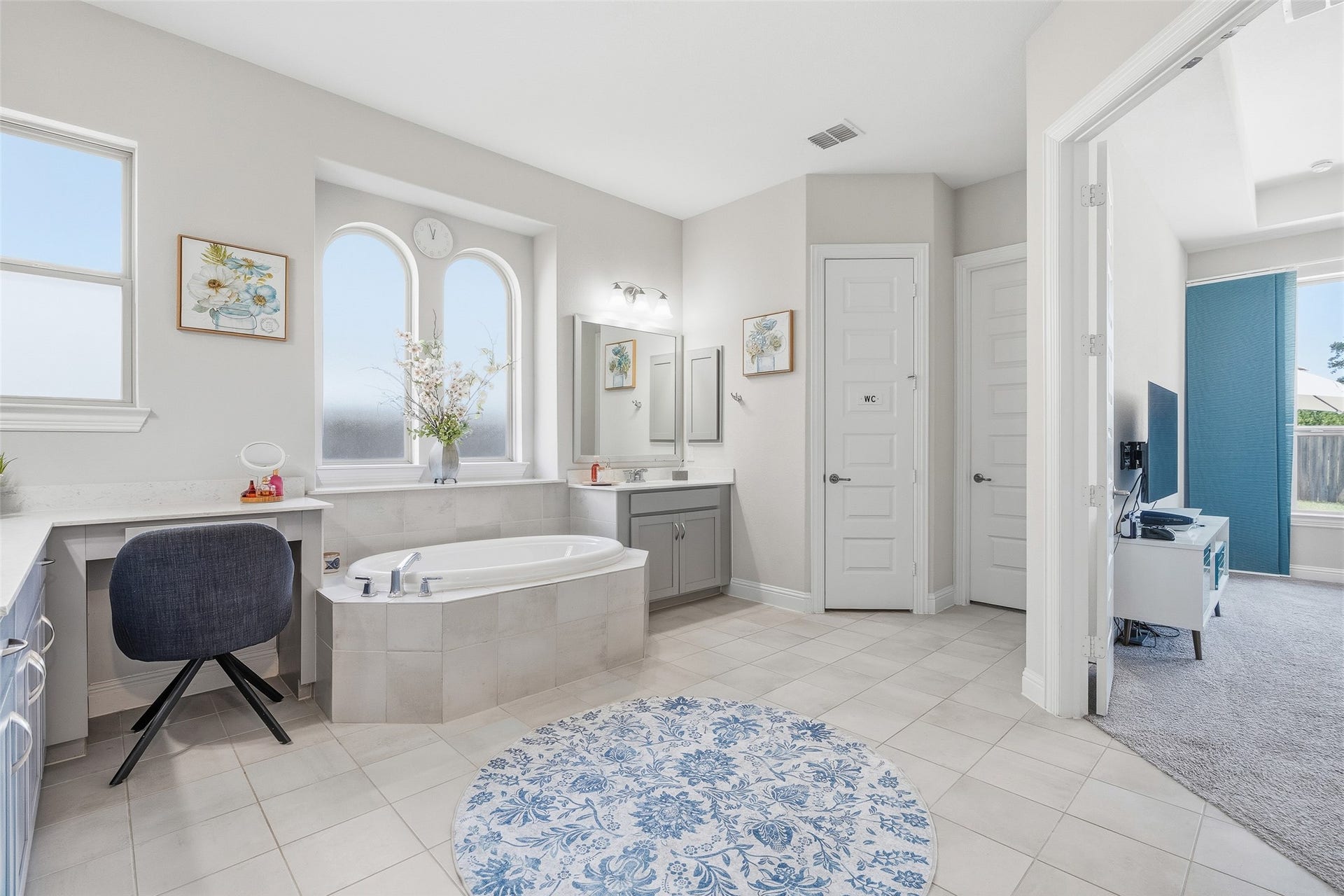 A spacious en suite bath offers dual sinks, storage, private toilet, a large soaking tub, separate shower with bench, vanity, and 2 large walk-in closets with ample storage and access to the laundry room.