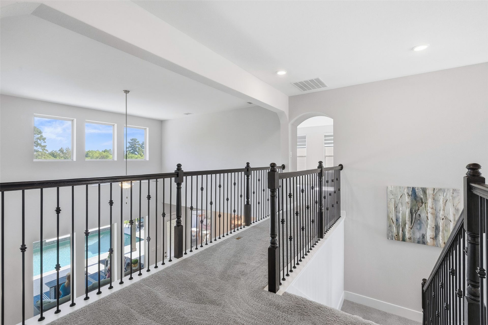 Top of the stairs on second floor overlooks formal dining, living, kitchen and pool.