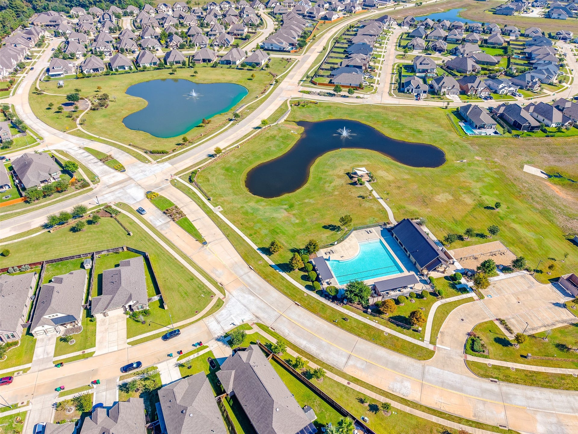 A bird's-eye view of the community amenities, including a pool with a accessible entry chair, Clubhouse & playground, covered picnic area (near pond), a pocket park with a future playground (top left), and 2 of the 3 catch-and-release fishing ponds.