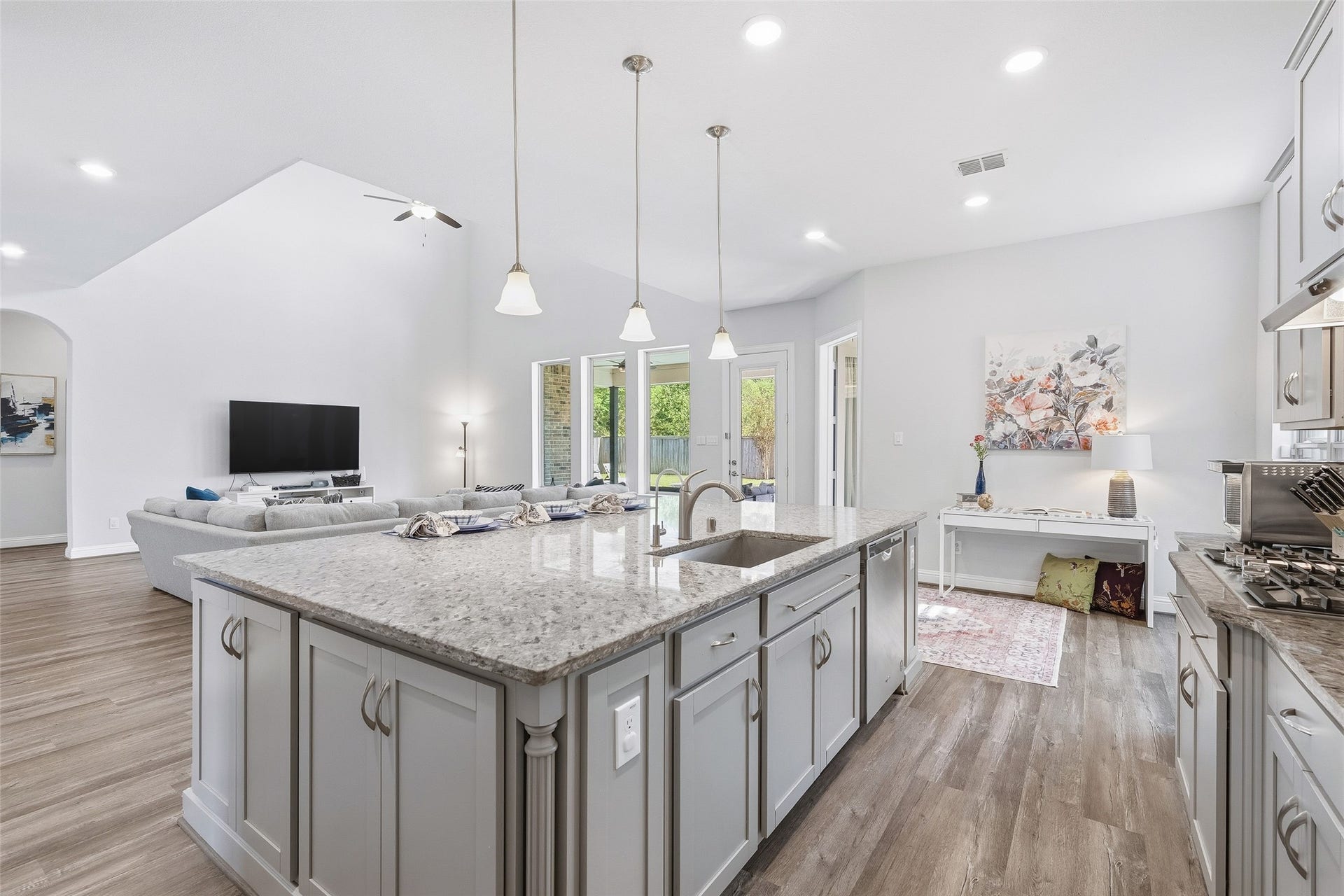 Enjoy an open-concept layout that flows seamlessly from the kitchen into the living area, enhanced by tall ceilings that create an airy, spacious atmosphere. Generous wall space easily accommodates large-scale artwork or an entertainment setup, while the granite island provides ample workspace, convenient storage on three sides, and comfortable barstool seating. The entire space overlooks the pool, creating a bright and inviting setting for everyday living and entertaining.
