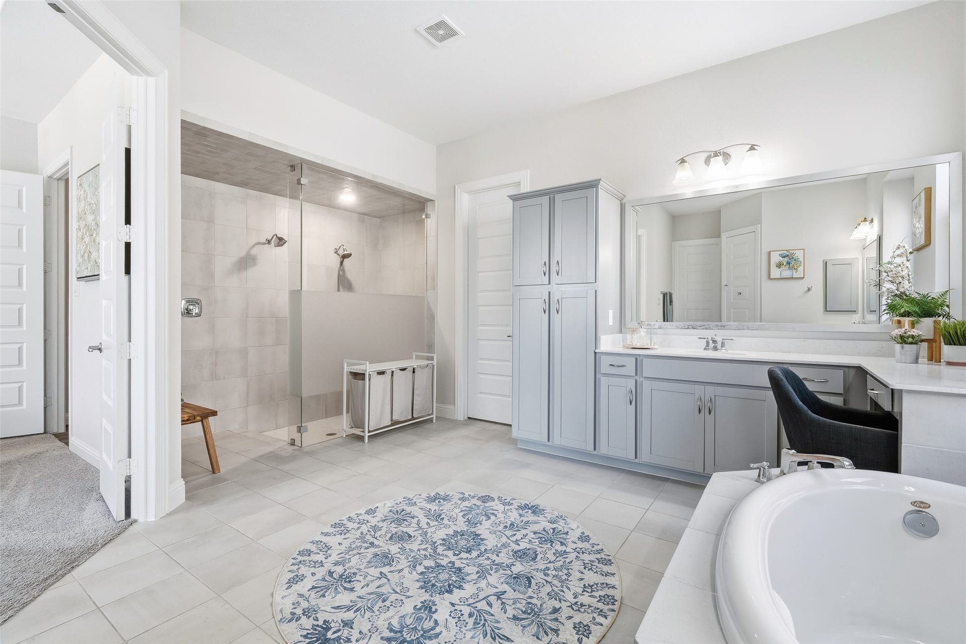 A spacious en suite bath offers dual sinks, storage, private toilet, a large soaking tub, separate shower with bench, vanity, and 2 large walk-in closets with ample storage and access to the laundry room.
