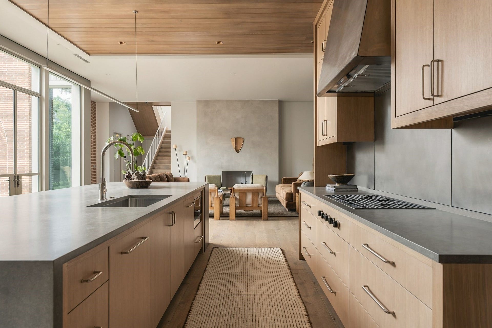 Designed for connection, the kitchen opens seamlessly to the family room while the wall of windows keeps the surrounding landscape at the forefront. The oversized island creates a natural gathering point, allowing everyday living & entertaining to flow effortlessly between the two spaces.